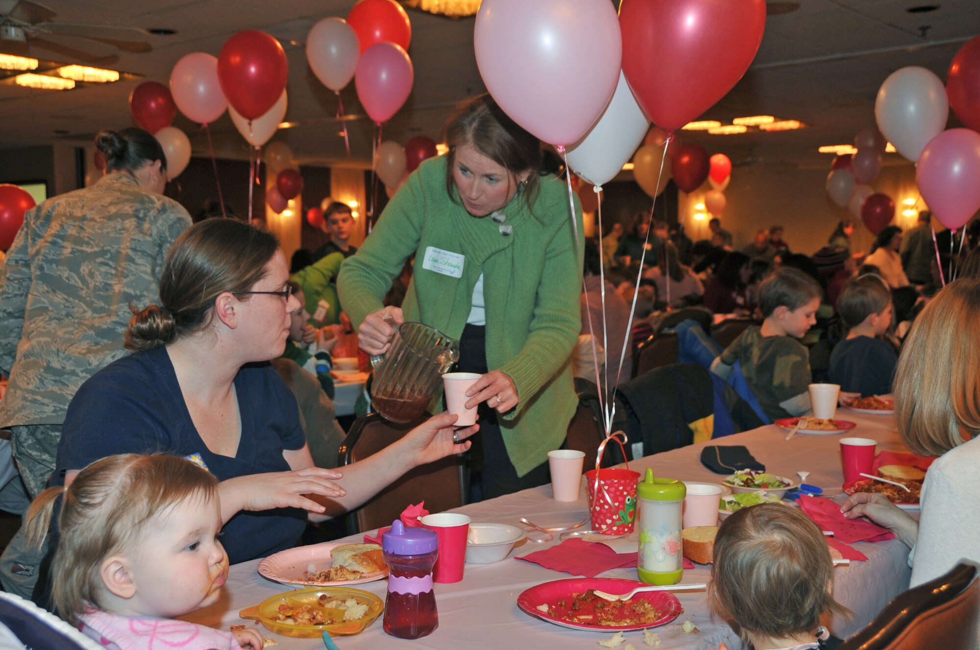 OFFUTT AIR FORCE BASE, Neb. -- Laura Shanahan, wife of 55th Wing Commander Brig. Gen. John N.T. Shanahan, offers iced tea to Audrey Maston, wife of 38th Reconnaissance Squadron member Capt. Chris Maston, during the deployed family dinner at the community center Feb. 9. Captain Maston is currently deployed. Organizations and volunteers from across Offutt and in the local community come together each quarter to plan an event for the families of deployed military members. This event featured a free dinner and games for children and educational guidance for spouses to help them with separation. U.S. Air Force photo by Jeff W. Gates.