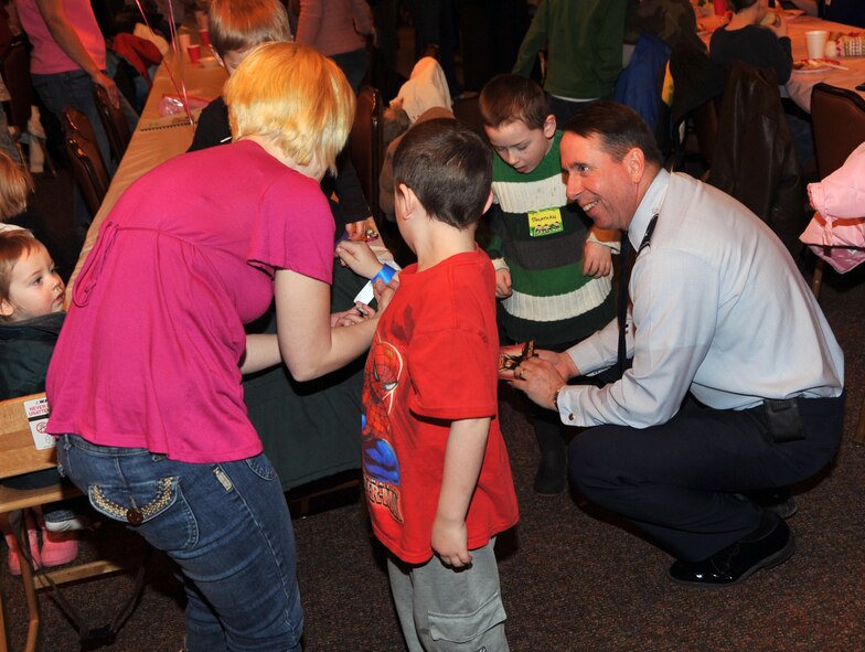 OFFUTT AIR FORCE BASE, Neb. -- Brig. Gen. John N.T. Shanahan, 55th Wing commander, talks with Holly Battishill and her sons Dean and Jonathon during the deployed family dinner at the community center Feb. 9. Her husband, Airman 1st Class Tyler Battishill, is assigned to  the 97th Intelligence Squadron but is currently deployed. Organizations and volunteers from across Offutt and in the local community come together each quarter to plan an event for the families of deployed military members. This event featured a free dinner and games for children and educational guidance for spouses to help them with separation. U.S. Air Force photo by Jeff W. Gates.