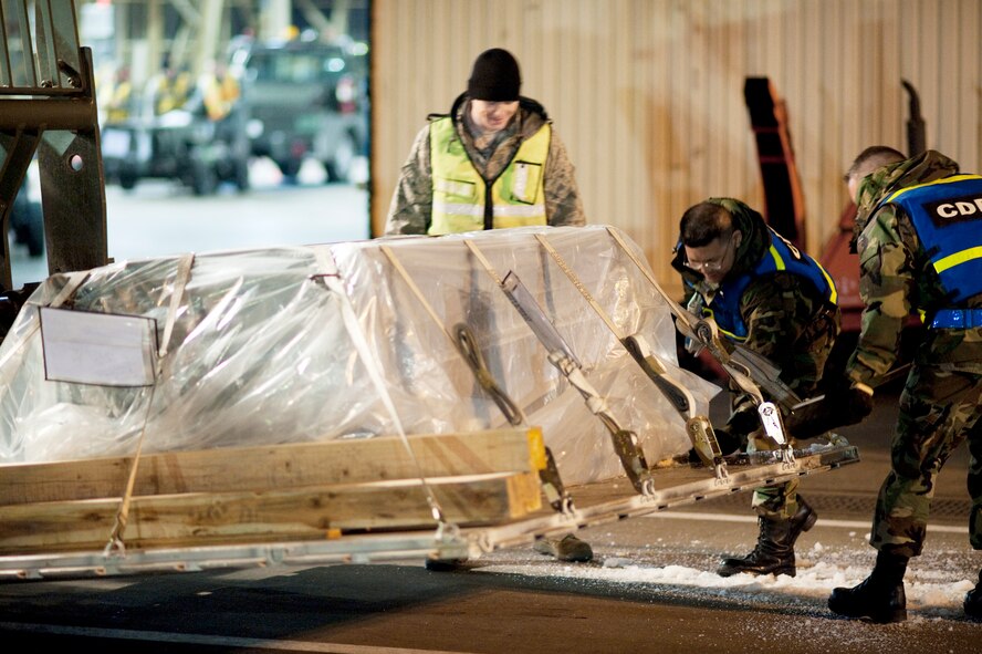 Airman 1st Class Alex Russell, Staff Sgt. Travis Baker and Staff Sgt. Ronald Stoll brush ice and snow off of an aircraft pallet outside a hangar at Misawa Air Base, Japan, during an operational readiness exercise Jan. 28, 2010. The snow had to be removed in order to get an accurate weight for flight. (U.S. Air Force photo/Staff Sgt. Samuel Morse)