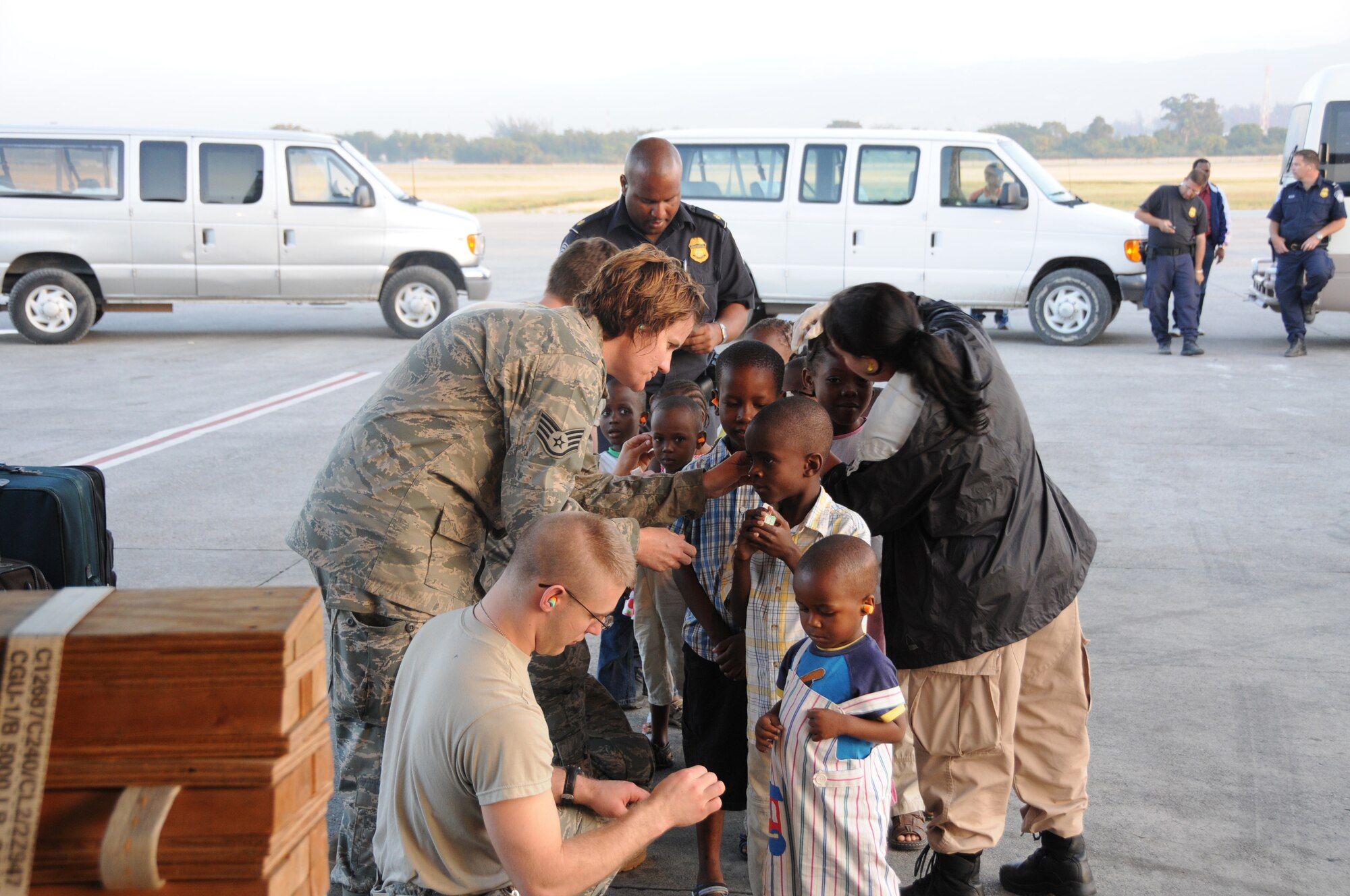 Members of West Virginia's Air National Guard's 134th Air Lift Wing "Charlie West" aid the latest Haitian orphans with ear protection prior to boarding the C-130. The 134th AW transported the latest group of Haitian orphans to the US. (U.S. Air Force photo/Staff Sgt. Peter Dean)
