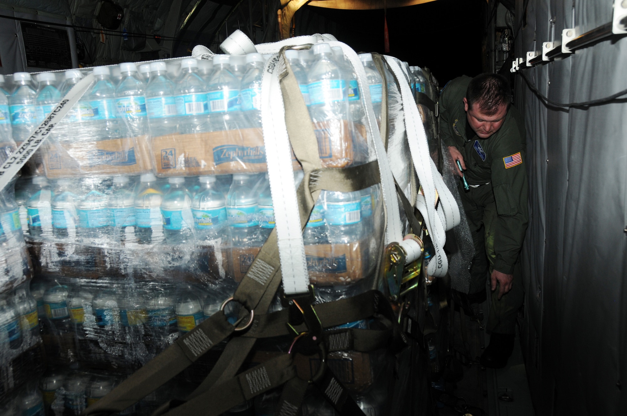 Senior Master Sgt. Thomas Obrochta 107th C-130 load master ensures that the pallets of water destine for Haiti are secure. "Everything needs to be secured for flight," said Obrochta." If it's not bolted down, it gets strap it down," he added.  The 107th has provided crews along with aircraft for the transportation of supplies into and evacuees out of Haiti since four days after the earthquake hit.  (U.S. Air Force photo/Staff Sgt. Peter Dean)