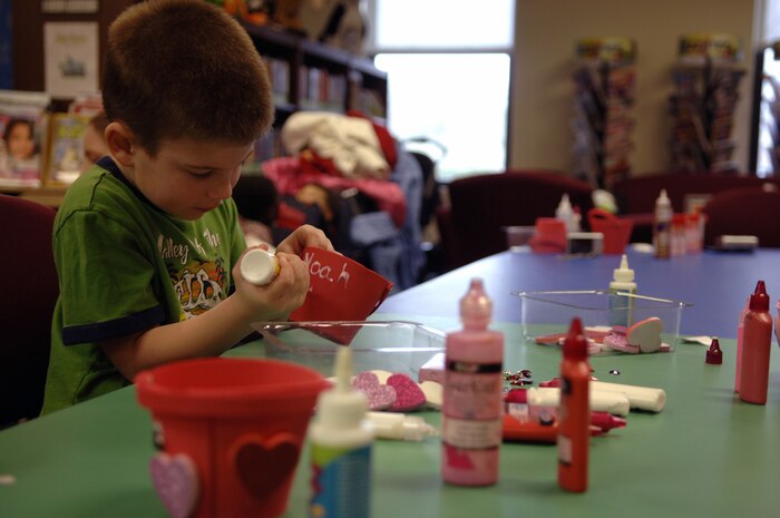 Noah Carter writes his name in glue on a valentine during the Valentine's Day Story Hour held at the base library here Feb. 9. The arts and crafts were one of many activities to entertain the children during the weekly story hour held every Tuesday.The children participated in a sing-a-along, a story reading and snack time. Noah is the son of Marine Corps Reserve Capt. David Carter. (U.S. Air Force Photo/Airman 1st Class Lauren Main)