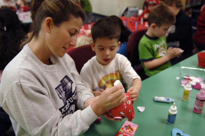 Marcy Carter assists her son Christian while making valentines during the Valentine's Day Story Hour at the base library here Feb. 9. Activities included a story reading, sing-a-longs and snack time. The story hour is held every Tuesday for spouses and their children. Christian is the son of Marine Corps Reserve Capt. David Carter. (U.S. Air Force Photo/Airman 1st Class Lauren Main)