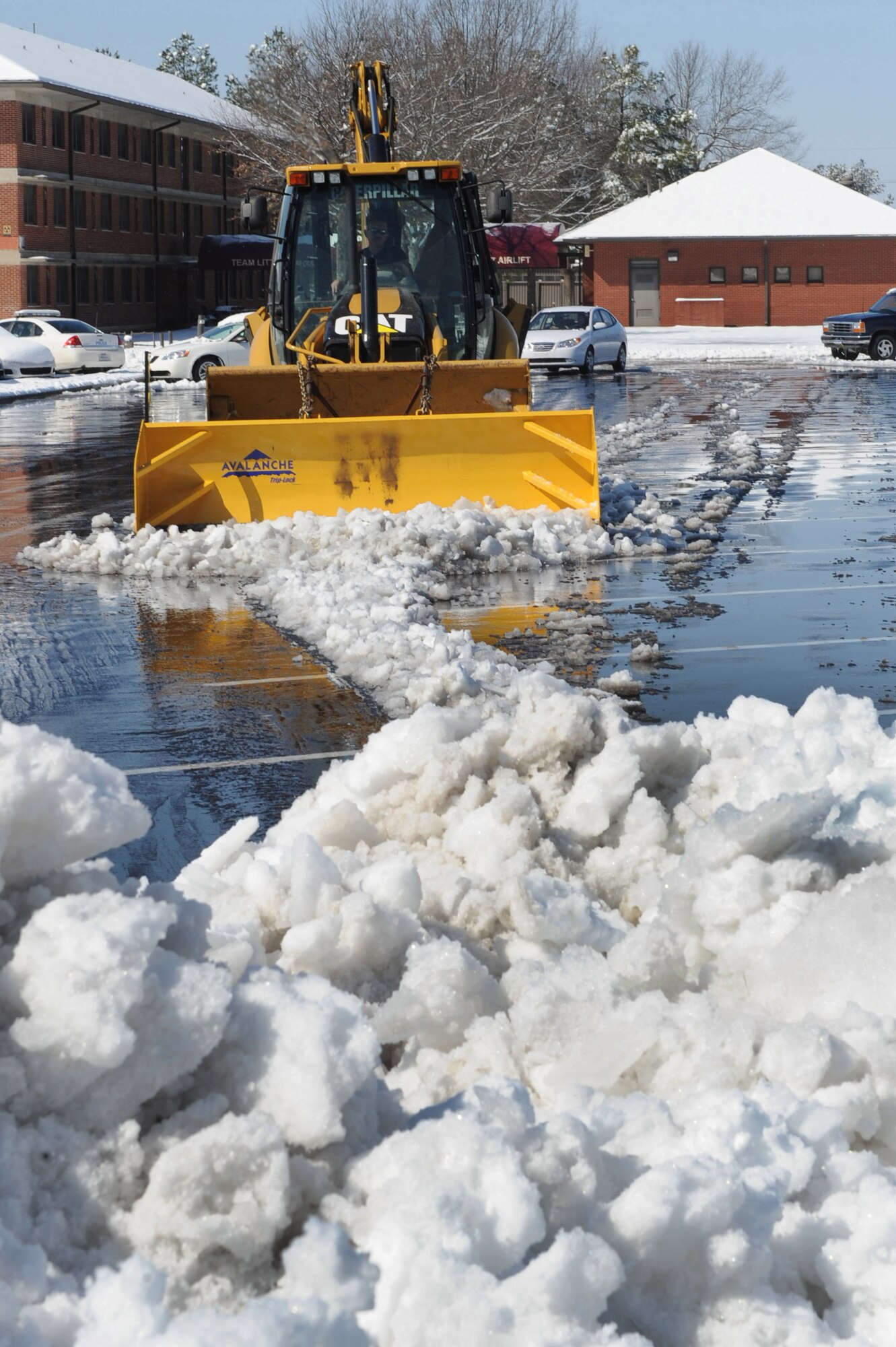 David Cole, 19th Civil Engineer Squadron heavy equipment operator, plows snow, ice and water Feb. 9 from the base dining facility parking lot. Mr. Cole is operating a Caterpillar backhoe with an Avalanche box blade snow plow attachment to better plow the large volume of snow and ice on the dining facility parking lot. (U.S. Air Force photo by Staff Sgt. Chad Chisholm)