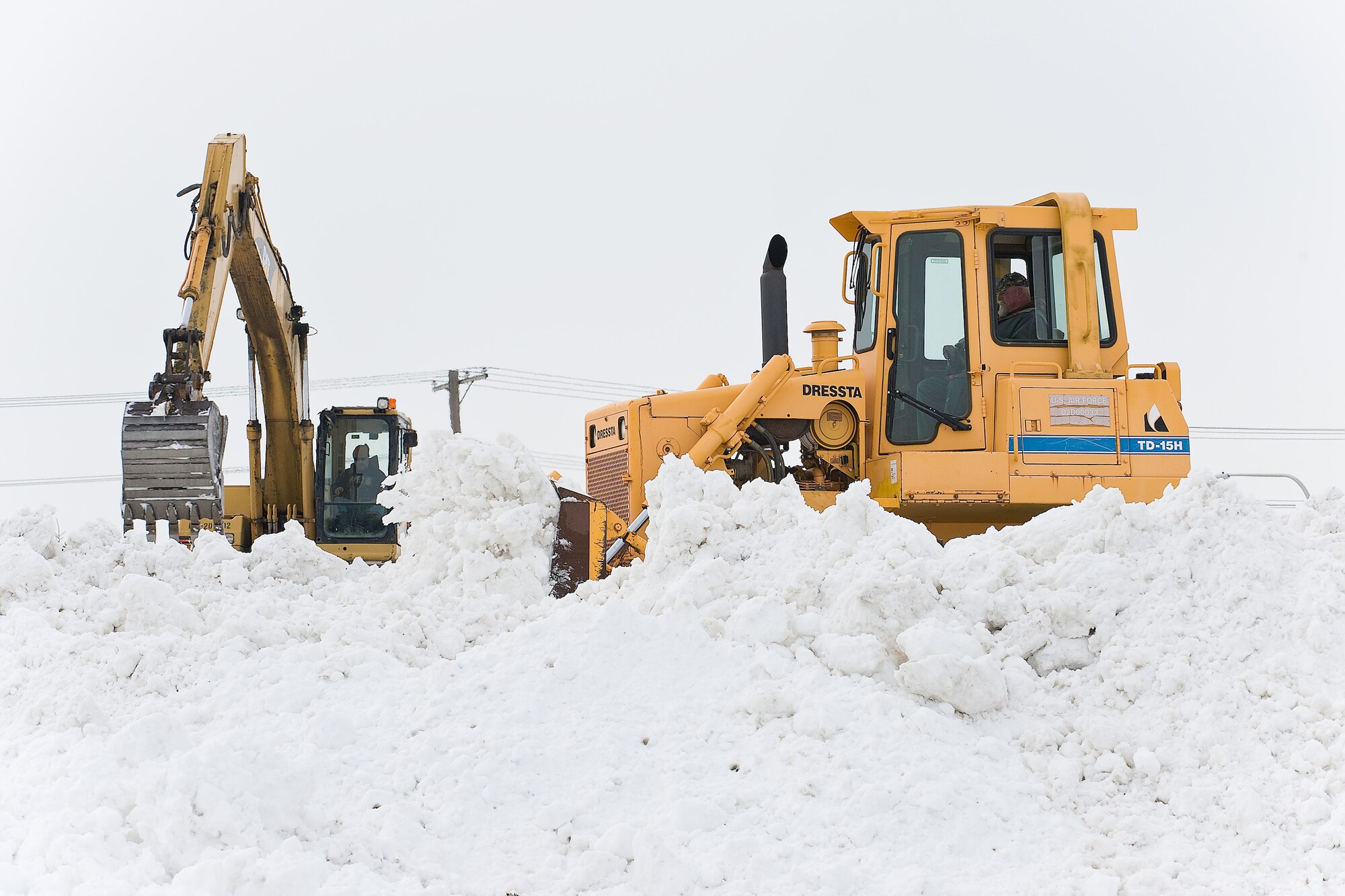 Team Dover members mold a snow mound behind the Education Trailers at Dover Air Force Base.  While removing snow from the flightline and runways at Dover AFB, crews dumped the snow behind the Education Trailers and The Landings Club to prevent snow mounds from forming along the runway and preventing aircraft from taxiing along the runway.. (U.S. Air Force photo/Roland Balik)