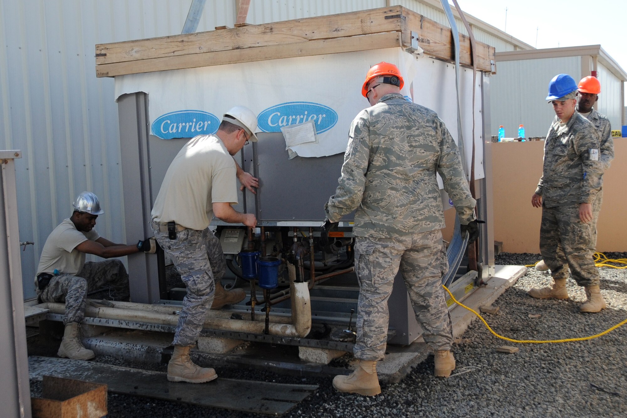 Members of the 380th Expeditionary Civil Engineer Squadron remove an air conditioning unit from the dining facility at an undisclosed location in Southwest Asia on Feb. 10, 2010.  A new unit was installed to increase the cooling efficiency for the building before summer temperatures rose.(U.S. Air Force photo/Senior Airman Jenifer H. Calhoun/Released)
