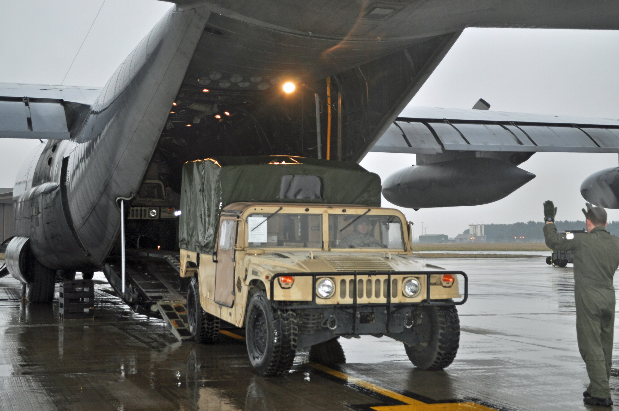 RAF MILDENHALL, England -- Airman 1st Class Anthony Vaticalos, 67th Special Operations Squadron loadmaster, uses hand signals to direct a Humvee laden with donations for Haiti into the back of a 352nd Special Operations Group MC-130P Combat Shadow, here, Feb. 5.  The 352nd Maintenance Squadron spearheaded a donation effort, collecting about 15,000 pounds of items ranging from toiletries to food to clothing, to assist in Haiti relief efforts.   (U.S. Air Force photo/Tech. Sgt. Marelise Wood)