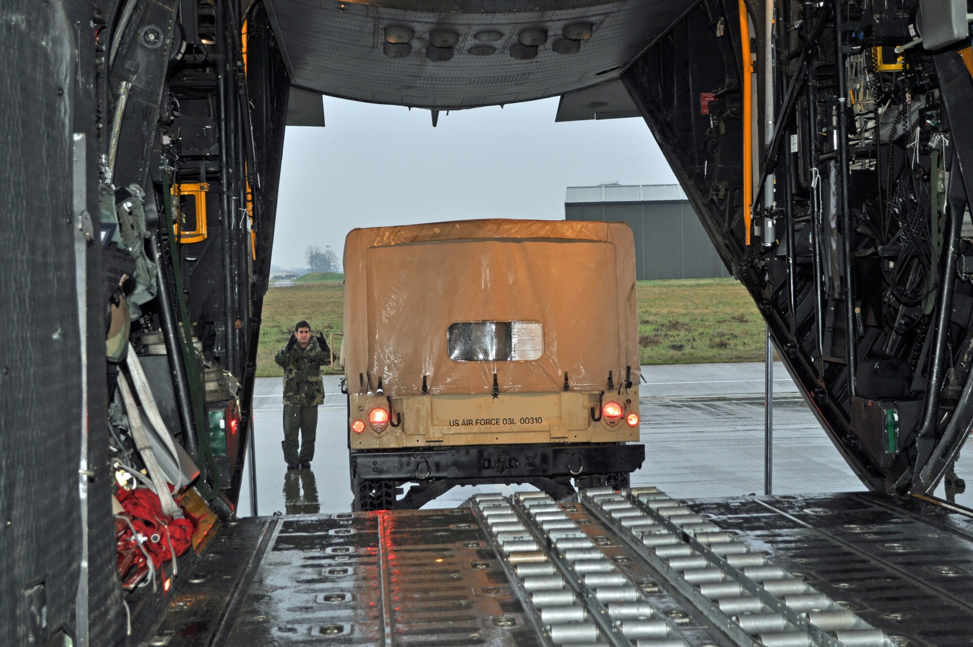 RAF MILDENHALL, England -- Senior Airman Caleb Henderson, 67th Special Operations Squadron loadmaster, directs a Humvee, packed with donations for Haiti here, Feb. 5.  The aircraft is an MC-130P Combat Shadow from the 352nd Special Operations Group.  The 352nd Maintenance Squadron spearheaded a donation effort, collecting about 15,000 pounds of items ranging from toiletries to food to clothing, to assist in Haiti relief efforts.  (U.S. Air Force photo/Tech. Sgt. Marelise Wood)