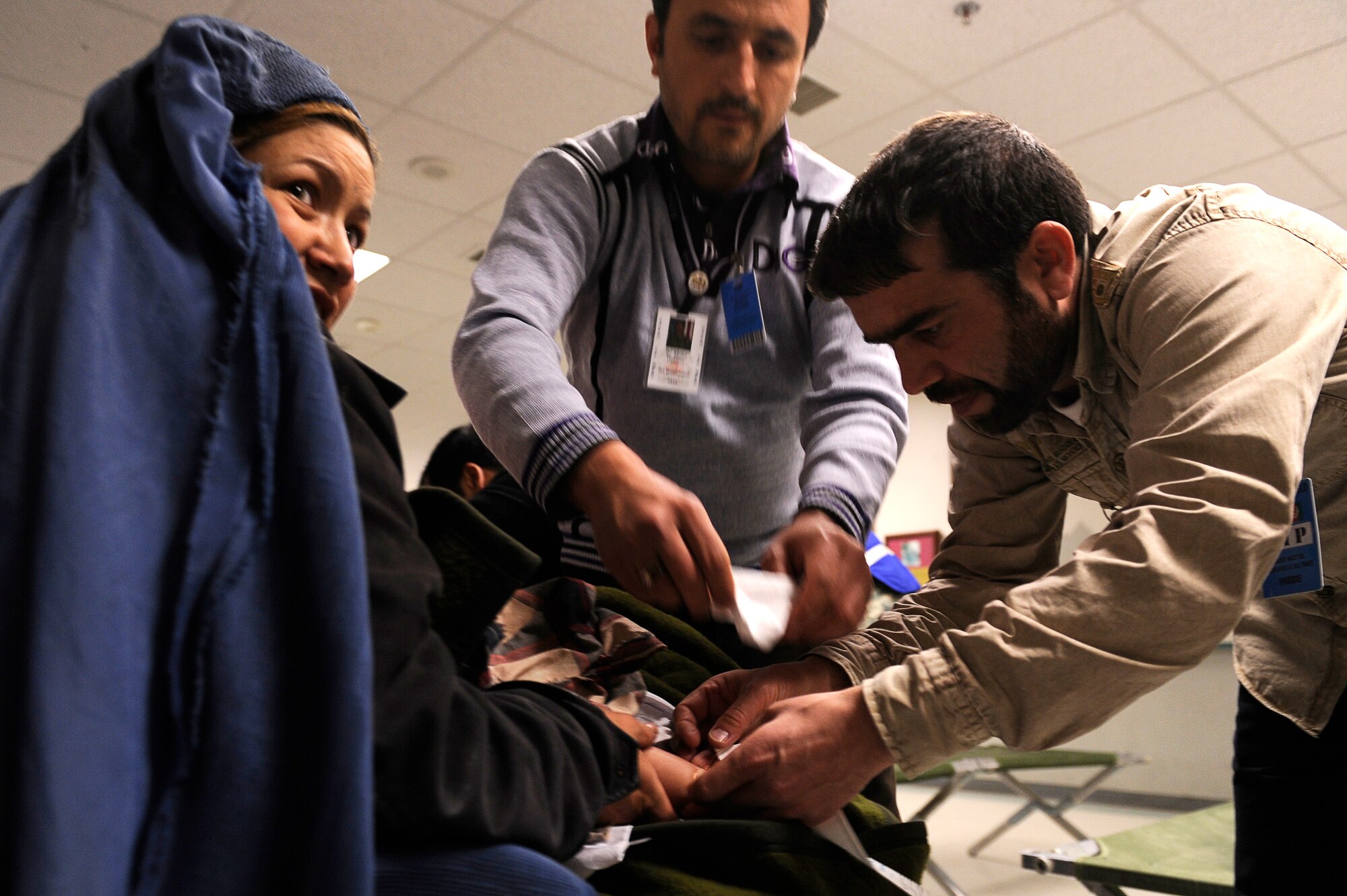 Afghan doctors Abdul Hashim (left) and Shekib Hassanzada put socks on a young avalanche survivor at Craig Joint Theater Hospital, Bagram Airfield, Feb. 9, 2010. Dozens of Afghans were taken to Bagram Airfield after an avalanche struck a mountain pass in the Parwan providence in north eastern, Afghanistan. (U.S. Air Force photo by/ Tech. Sgt. Jeromy K. Cross/released)