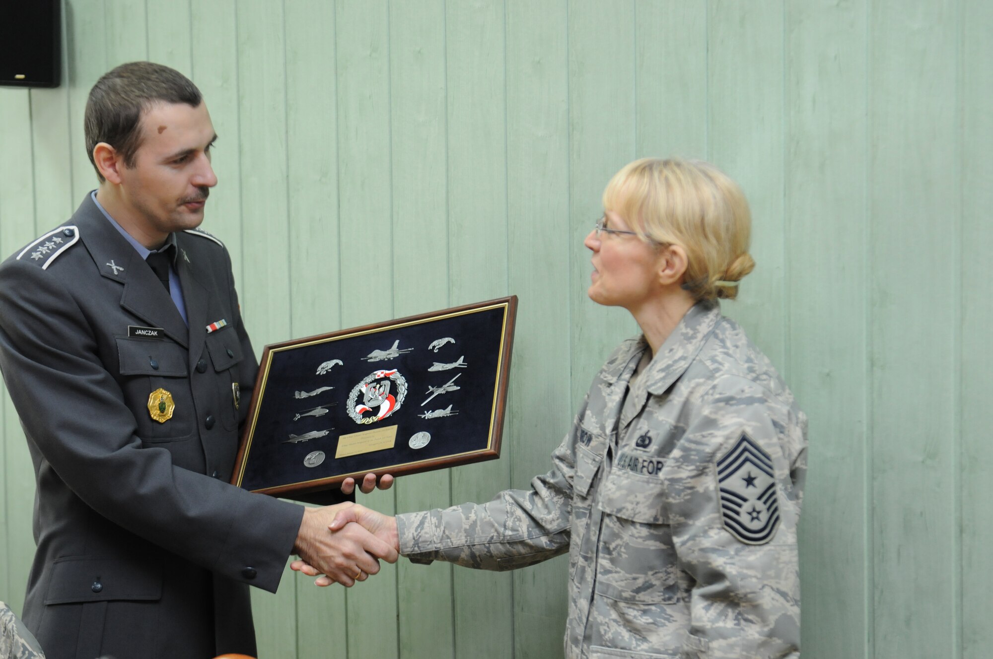 Chief Master Sgt. Grzegorz Janczak, Poland’s Chief Master Sergeant of the Air Force, presents a plaque to Chief Master Sgt. Pamela Derrow, USAFE command chief, as thanks for her visit to Poland to talk enlisted development issues with Polish Air Force leaders, Jan 10-13. (U.S. Air Force Photo by Master Sgt. Gino Mattorano)