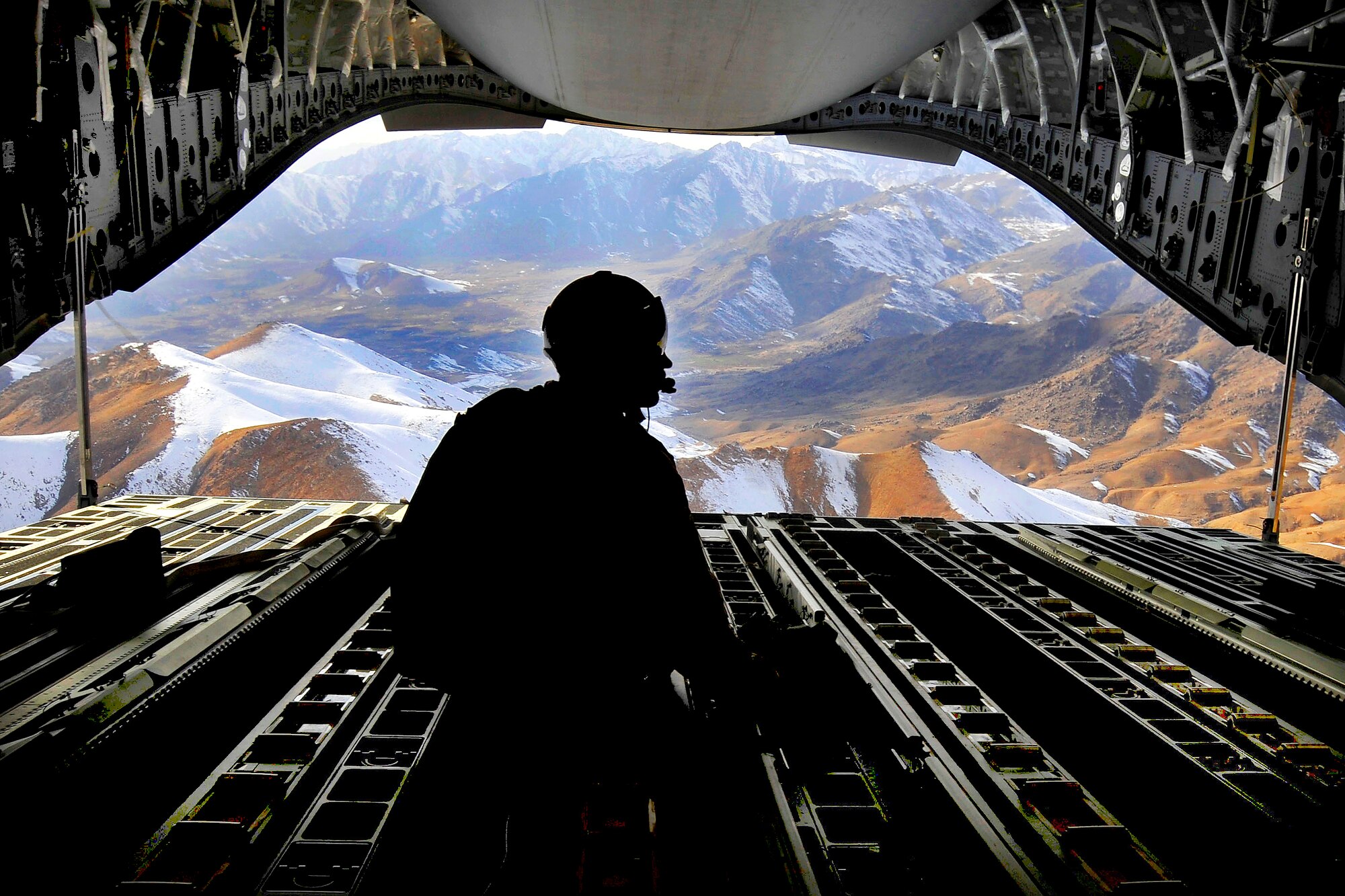 Tech. Sgt. Kevin Owens sits on the ramp of a C-17 Globemaster III aircraft while flying over the mountains of Afghanistan after an air delivery mission Feb. 2. Sergeant Owens and the crew delivered 34 container delivery system bundles to an undisclosed base in Afghanistan as part of a combat resupply mission. Sergeant Owens is a loadmaster with the 14th Airlift Squadron and is currently deployed to the Middle East with the 816th Expeditionary Airlift Squadron. (U.S. Air Force photo/Staff Sgt. Angelita Lawrence/Released)