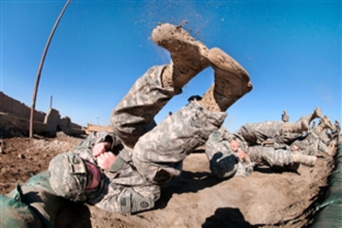 Dirt flies off a U.S. paratrooper's boots as he finishes a parachute landing fall with other paratroopers stationed on Camp Ramadi, Iraq, Feb. 5, 2010. The paratroopers are participating in a basic airborne refresher course taught by instructors visiting from Advanced Airborne School on Fort Bragg, N.C., to prepare for upcoming airborne exercises. The paratroopers are assigned to the 82nd Airborne Division's 1st Brigade, an Advise and Assist Brigade.