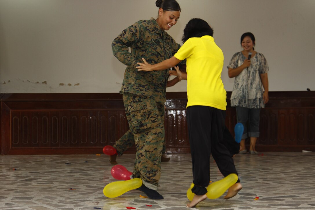Lance Cpl. Claudia Guerrero plays a game with one of the young ladies at Narisawat welfare Protection and Vocational Training Centre for Women here in Thailand Feb. 10. The objective of the game was to stomp and pop all other players’ balloons off their feet.