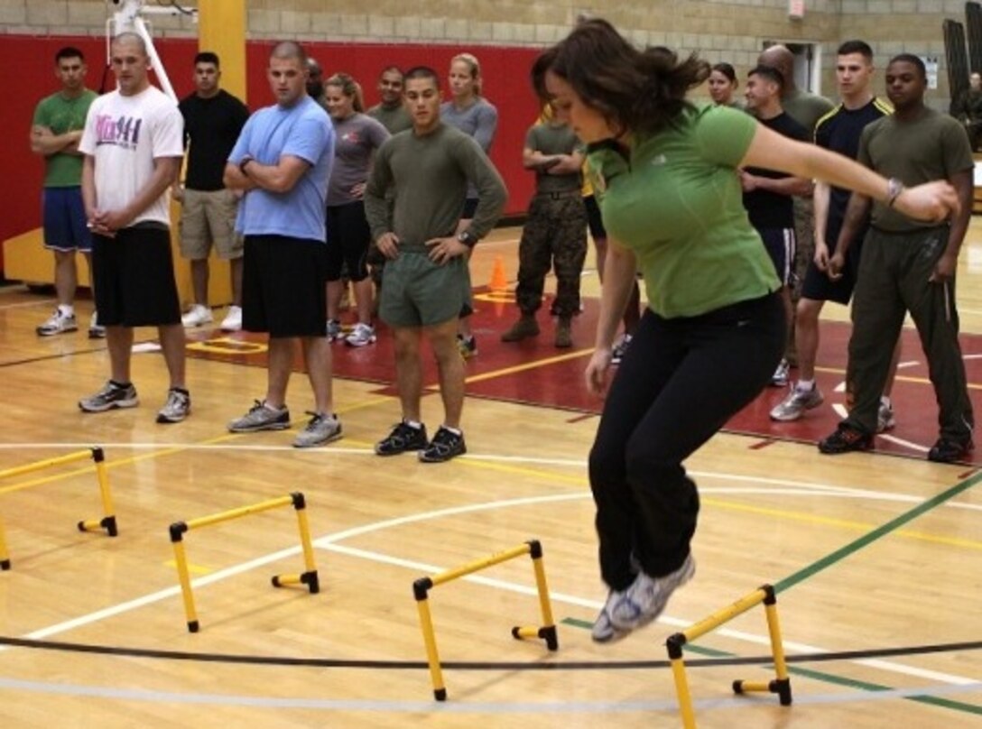 Annaleis Petrich, personal trainer, Semper Fit Division, Marine Corps Community Services, Camp Pendleton, demonstrates how to negotiate an obstacle in the 300 PFT/CFT training class at the Paige Fieldhouse fitness center, Feb. 10. Marine Corps Community Services offers free personal training services to all active-duty service members, their families and Department of Defense civilians. The personal trainers also provide guidance in group exercises and various Semper Fit training and health classes.