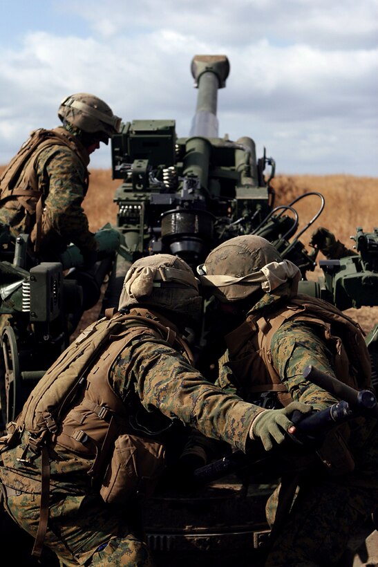Lance Cpl. Cody L. Spraggins, left, 20, an Arlington, Texas, native and artillery crewman with Battery E, 2nd Battalion, 12th Marine Regiment, 3rd Marine Division, III Marine Expeditionary Force, prepares to load a primer and charge as Pfc. Levi S. Minissale, middle, 20, a St. Cloud, Minn., native and artillery crewman with Battery E, and Lance Cpl. Cameron J. Smith, 19, Sacramento, Calif., native and motor transportation operator with Battery E, push an artillery round into the chamber of a M777 howitzer with a ram rod during the Hijudai Artillery Relocation Training Program Exercise at Hijudai Training Area, Japan, Feb. 3. The regularly-scheduled artillery training enables Marines to maintain their operational readiness to respond to any contingency where artillery, crew served weapons and small arms fire would be required.