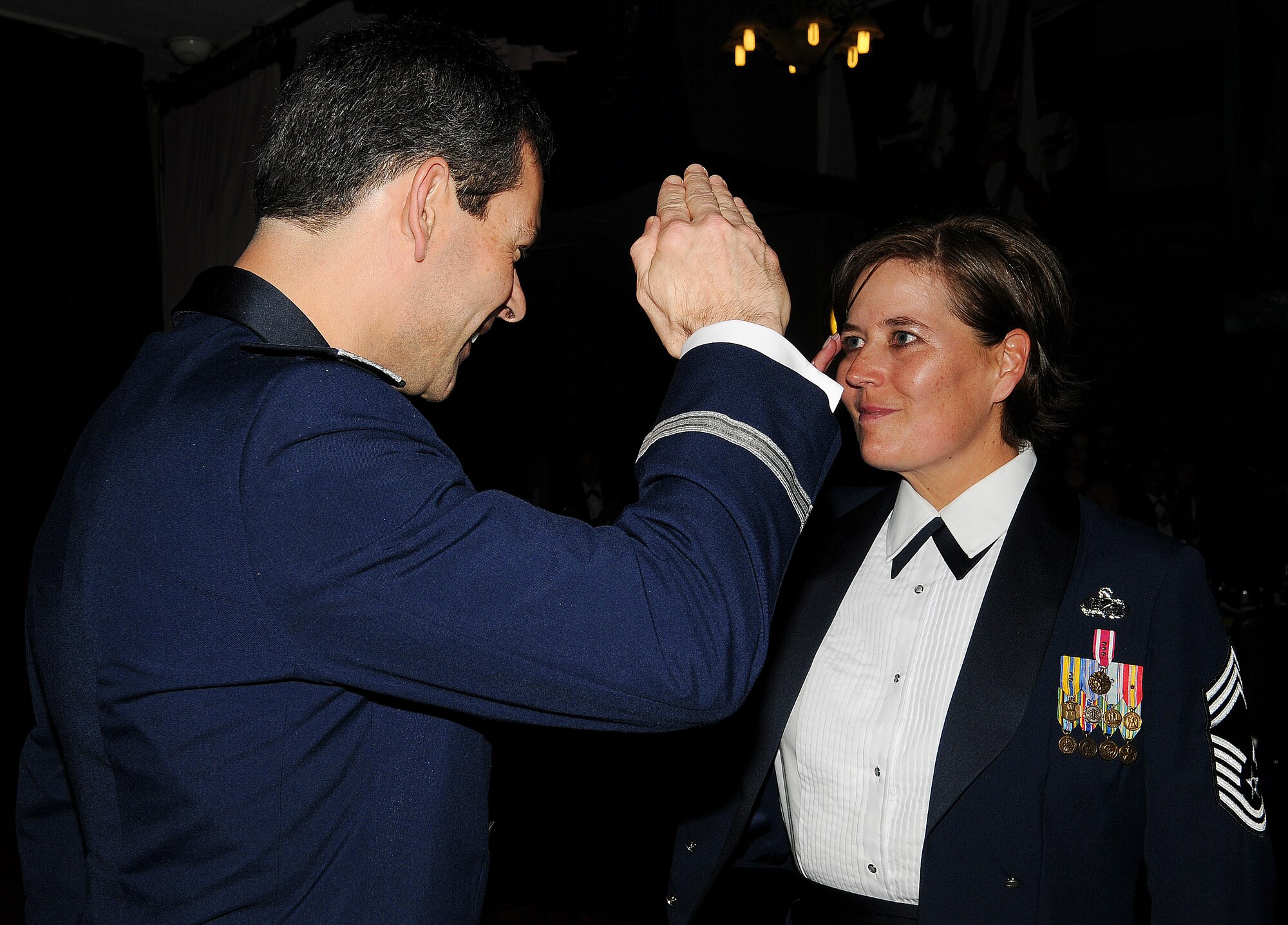 Brig. Gen. Kenneth Wilsbach, 18th Wing commander, coins Chief Master Sgt. Annette Henderson, Erwin Professional Military Education Center commandant, at the Non-Commissioned Officer Academy graduation at Kadena Air Base, Japan, Feb. 11. Chief Master Sgt. Annette Henderson retires Feb. 12 after 29 years of dedicated service to the United States Air Force. (U.S. Air Force photo / Senior Airman Amanda N. Grabiec)