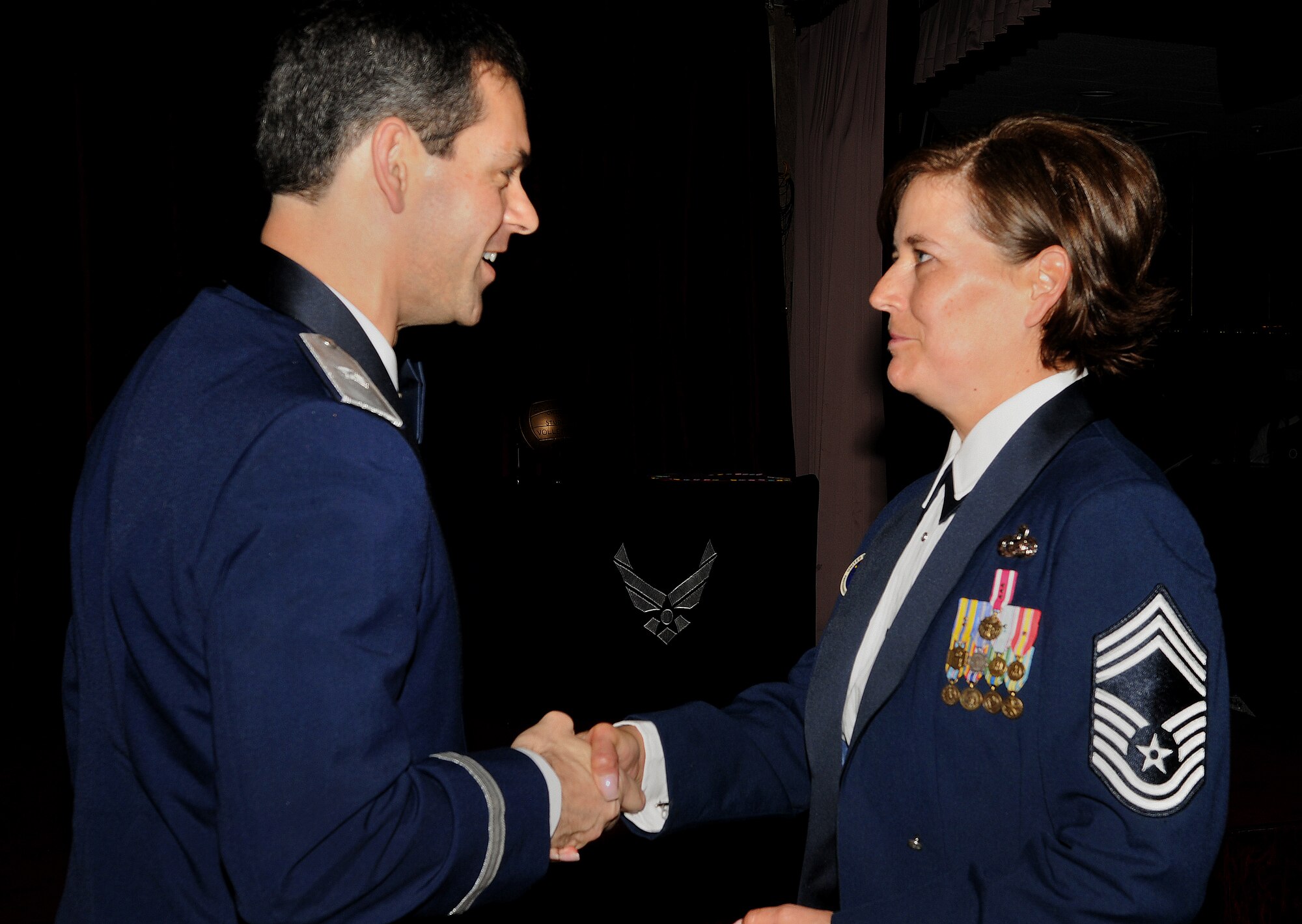 Brig. Gen. Kenneth Wilsbach, 18th Wing commander, coins Chief Master Sgt. Annette Henderson, Erwin Professional Military Education Center commandant, at the Non-Commissioned Officer Academy graduation at Kadena Air Base, Japan, Feb. 11. Chief Master Sgt. Annette Henderson retires Feb. 12 after 29 years of dedicated service to the United States Air Force. (U.S. Air Force photo / Senior Airman Amanda N. Grabiec)