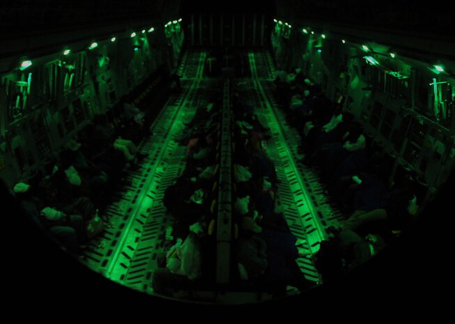 Evacuees from Haiti sit in a dimly lit C-17 on its way to Charleston International Airport Feb. 6. A total of 75 evacuees were aboard the flight, including the elderly and infants. Evacuees carried little belongings, with some leaving behind family members who were not able to leave the country. As of Feb. 9, more than 700 evacuees have transited Charleston International Airport. (U.S. Air Force photo/Staff Sgt. Daniel Bowles)