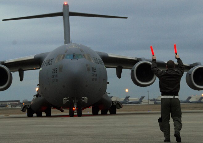 Capt. Tony Mione marshals a Dover AFB C-17 transporting evacuees from Haiti at Charleston International Airport Feb. 9. Aircraft on evacuations missions arriving at the airport are limited to 75 passengers per mission. As of Feb. 9, more than 700 evacuees had transited the airport. Captain Mione is the deputy chief of Wing Plans for the 437th Airlift Wing. (U.S. Air Force photo/Staff Sgt. Daniel Bowles)