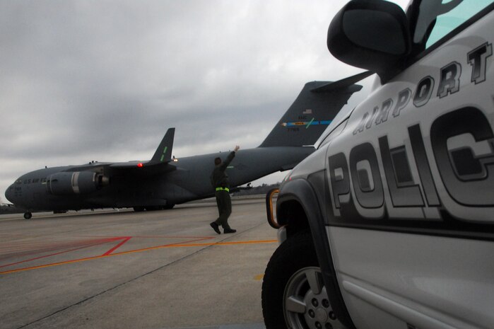 Lt. Col. John Donahue signals "all clear" to the aircrew of a taxiing Dover AFB C-17 after successfully transporting evacuees from Haiti to Charleston International Airport Feb. 9. Evacuee flights began arriving in Charleston Feb. 4, and Colonel Donahue is currently leading a team of officers acting as liaison between Air Force mission planners and local civilian authorities in charge of repatriation efforts. Colonel Donahue is the 628th Air Base Wing chief of Wing Plans. (U.S. Air Force photo/Staff Sgt. Daniel Bowles)