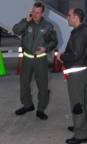 Lt. Col. John Donahue, left, makes a call shortly before the arrival of a C-17 transporting evacuees from Haiti to Charleston International Airport Feb. 9. Evacuee flights began arriving in Charleston Feb. 4, and the flights are currently being tracked by Colonel Donahue and four Air Force officers to provide flight information to civilian authorities in charge of repatriation efforts. Colonel Donahue is the 628th Air Base Wing chief of Wing Plans and was joined by 437th Airlift Wing Deputy Chief of Wing Plans Capt. Tony Mione, right, in greeting the evacuees on the airport parking ramp. (U.S. Air Force photo/Staff Sgt. Daniel Bowles)