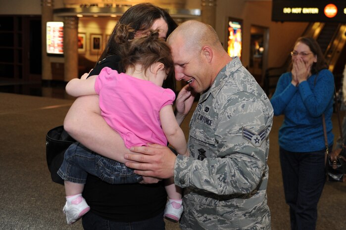NELLIS AIR FORCE BASE, Nev.-- Senior Airman Nicholas Dephilippis embraces his wife and daughter at the airport after returning from a deployment.  Approximately 25 members of the 99th Security Forces Squadron returned Jan. 31 from a deployment to Southwest Asia.  (U.S. Air Force photo by Tech. Sgt. Langford Saturnio)