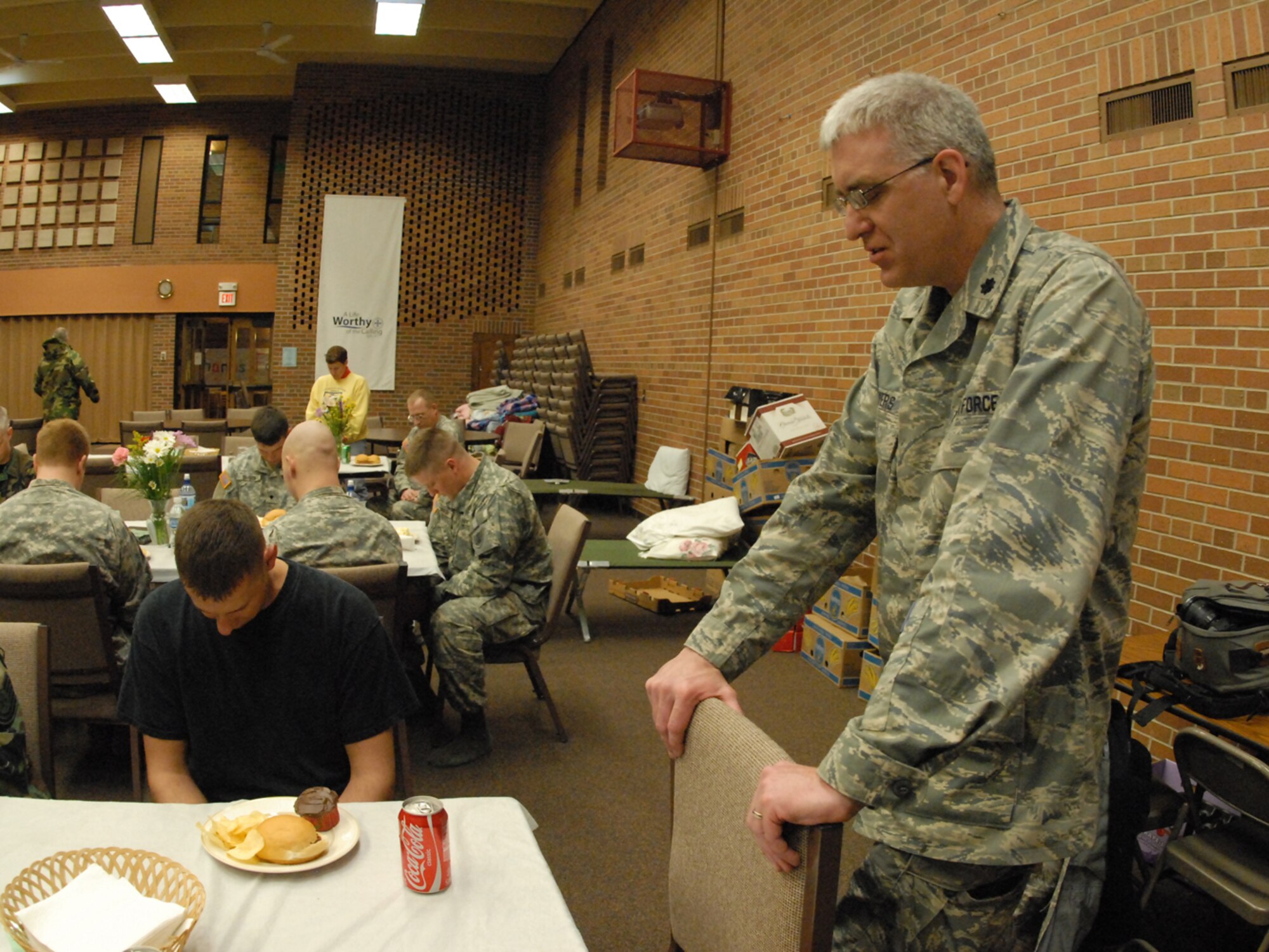 Chaplain Lt. Col. John Flowers, of the 119th Wing, says a prayer before a meal as he makes a morale visit to U.S. Army Soldiers and U.S. Air Force N.D. National Guard members as they remain on alert for rescue missions out of their Quick Response Force staging area at Olivet Lutheran Church, Fargo, N.D. on March 31. The military personnel were in place to respond to emergency evacuation requests of flood victims stranded by flood water of the Red River along the North Dakota - Minnesota border.  (DoD photo by Senior Master Sgt. David H. Lipp)