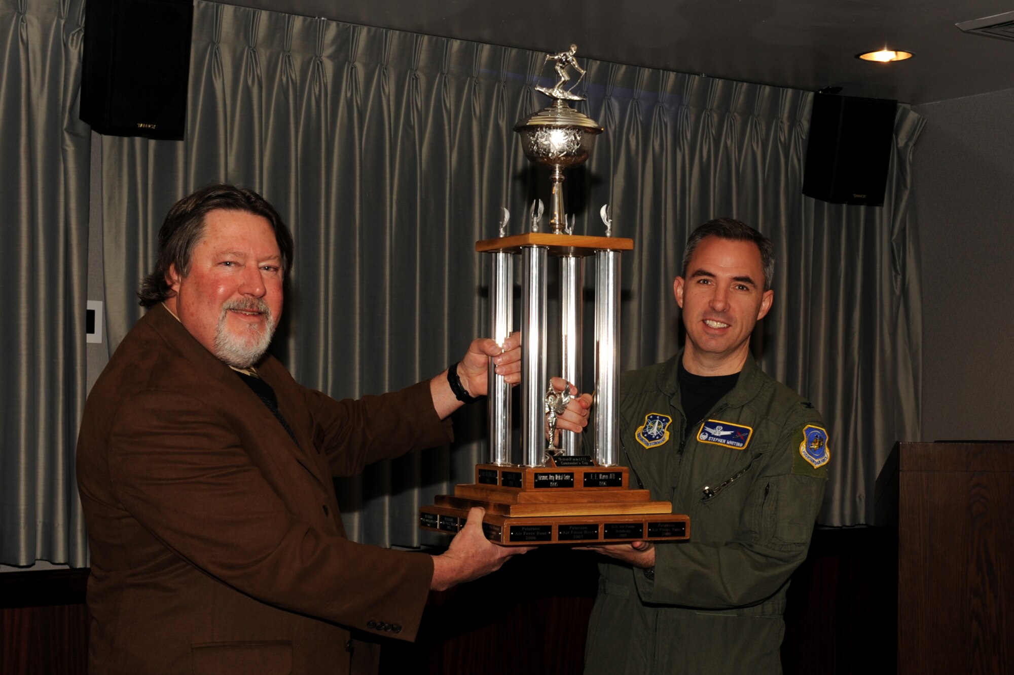 Warren Schroeder, 21st Force Support Squadron marketing, and Col. Stephen N. Whiting, 21st Space Wing commander, hoist the SnoFest Commander’s Cup, Feb. 3, in the wing conference room. Peterson skiers won the cup posting a combined time of 83.18 seconds in racing Jan. 29 at Keystone Resort. (U.S. Air Force photo/Roberta McDonald)