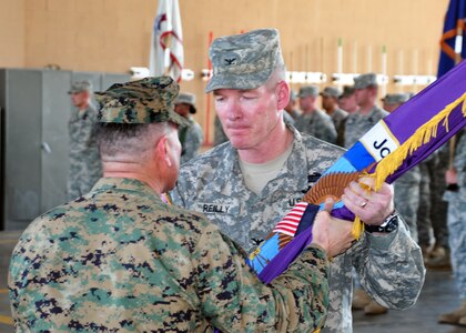 Army Col. Gregory Reilly accepts the colors and command of Joint Task Force-Bravo from the presiding officer Marine Corps Brig. Gen. David Garza, chief of staff, U.S. Southern Command, during a change of command ceremony at the Soto Cano Fire Department February 9. (U.S. Air Force Photo/Staff Sgt. Bryan Franks)