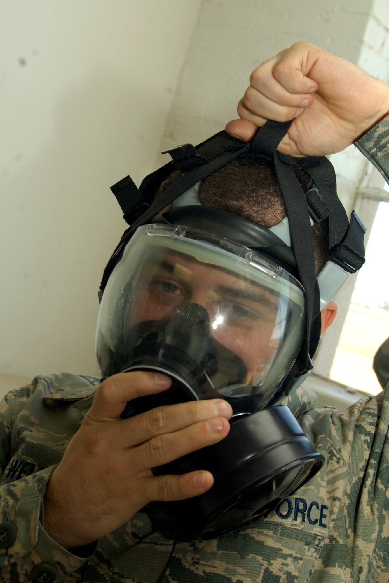 Senior Airman Brian Wells, a 22nd Aircraft Maintenance Squadron guidance and control maintenance technician, tightens his gas mask to ensure it fits properly, Jan. 26, 2010, during a survival skills training class at McConnell Air Force Base, Kan.  Emergency management instructors provide gas mask training to active-duty and Guard member here before they deploy. One complete, training certification lasts two years. (U.S. Air Force photo/Airman 1st Class Andrea Salazar)