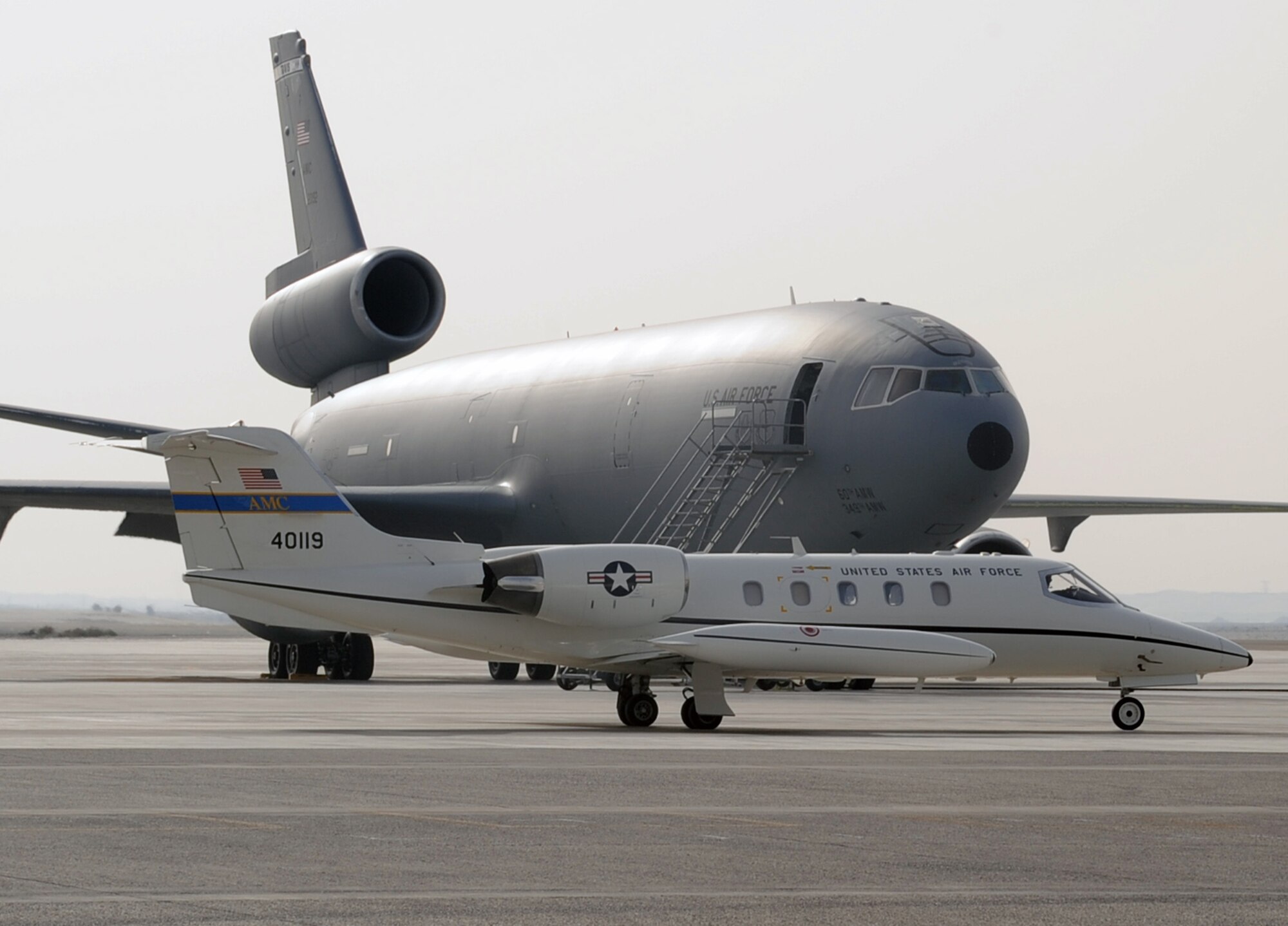 An Air Mobility Command C-21 aircraft taxis in front of the deployed KC-10 Extender on the parking ramp of a non-disclosed base in Southwest Asia. Both aircraft are part of Air Mobility Command which provides airlift, air refueling, aeromedical evacuation and other mobility functions in support of overseas contingency operations all around the world.  (U.S. Air Force Photo/Master Sgt. Scott T. Sturkol/380th Air Expeditionary Wing Public Affairs)