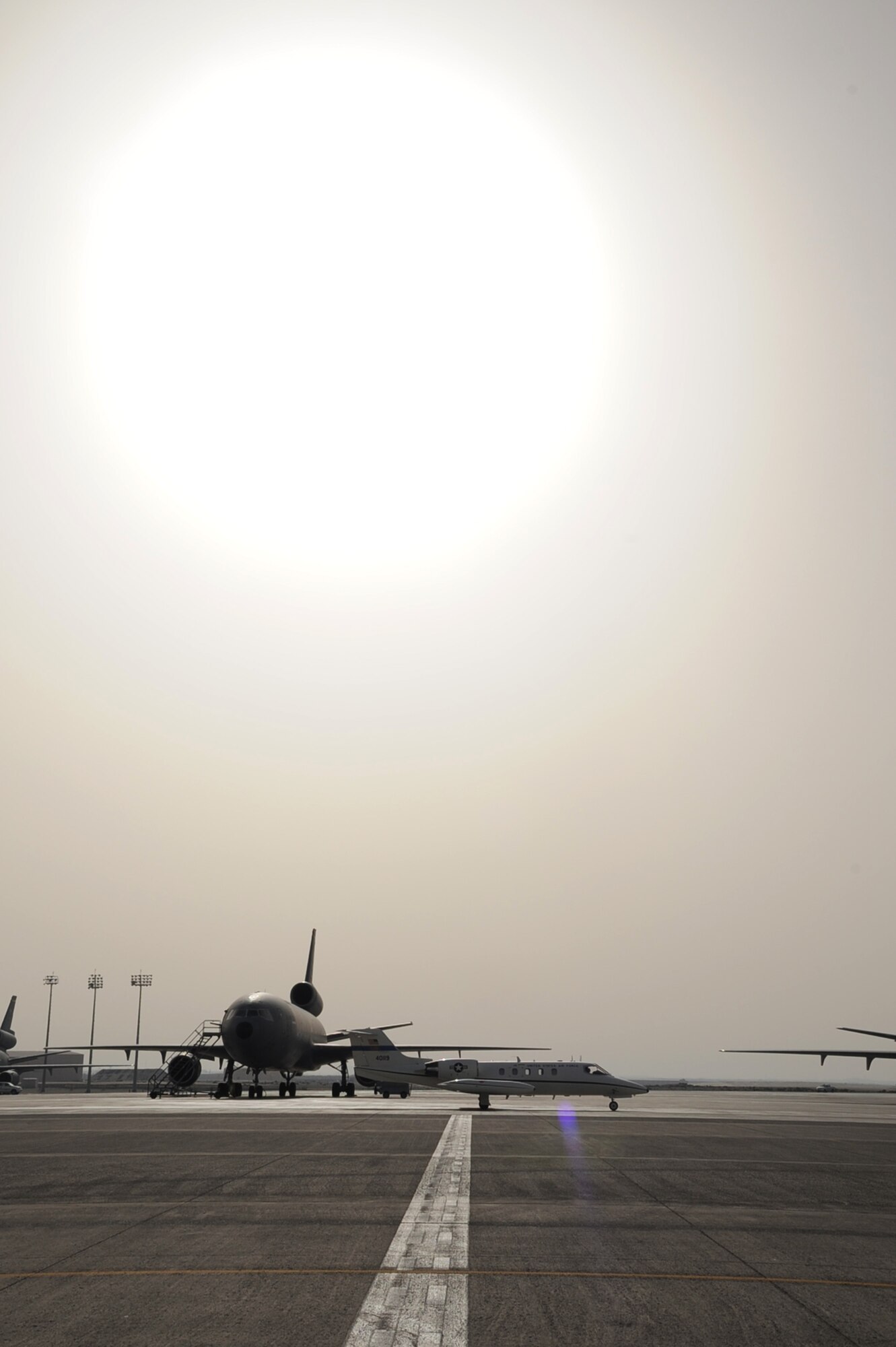An Air Mobility Command C-21 aircraft taxis in front of the deployed KC-10 Extender on the parking ramp of a non-disclosed base in Southwest Asia. Both aircraft are part of Air Mobility Command which provides airlift, air refueling, aeromedical evacuation and other mobility functions in support of overseas contingency operations all around the world.  (U.S. Air Force Photo/Master Sgt. Scott T. Sturkol/380th Air Expeditionary Wing Public Affairs)