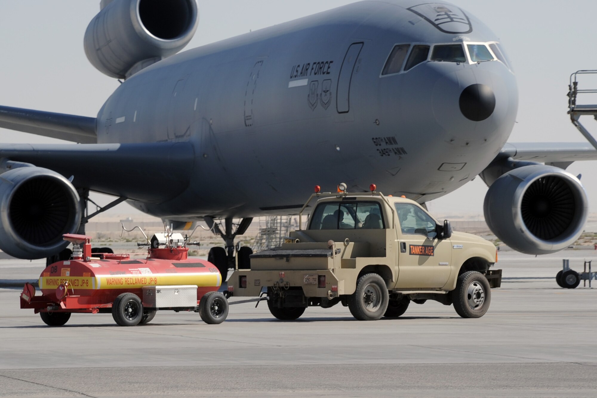 Maintenance Airmen drive a vehicle towing jet fuel reclamation equipment to a KC-10 Extender during operations at a non-disclosed base in Southwest Asia on Feb. 10, 2010.  The KC-10 Extender is a part of the 908th Expeditionary Air Refueling Squadron of the 380th Air Expeditionary Wing. KC-10s assigned to the 908th EARS fly combat air refueling missions in support of Operations Enduring Freedom, the Combined Joint Task Force-Horn of Africa and Operation Iraqi Freedom. The KC-10 is the Air Force's largest tanker and in 2009, aircraft assigned to the 908th EARS flew more than 4,700 combat missions offloading more than 422 million pounds of fuel to more than 31,400 aircraft.  (U.S. Air Force Photo/Master Sgt. Scott T. Sturkol/Released)