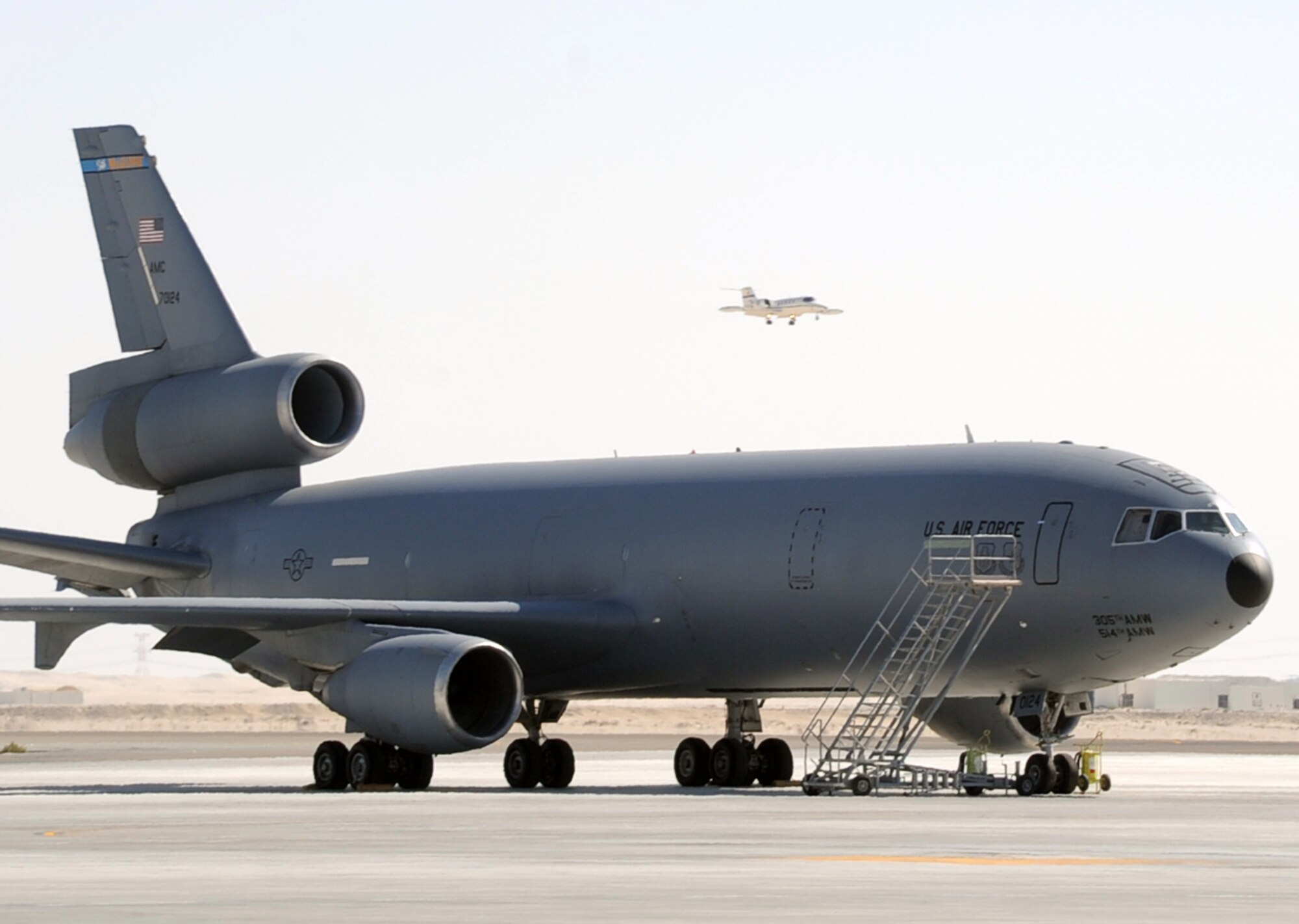 An Air Mobility Command C-21 is seen coming in for a landing over a parked KC-10 Extender at a non-disclosed base in Southwest Asia on Feb. 10, 2010.  The KC-10 Extender, deployed from Travis Air Force Base, Calif., is a part of the 908th Expeditionary Air Refueling Squadron of the 380th Air Expeditionary Wing. KC-10s assigned to the 908th EARS fly combat air refueling missions in support of Operations Enduring Freedom, the Combined Joint Task Force-Horn of Africa and Operation Iraqi Freedom. The KC-10 is the Air Force's largest tanker and in 2009, aircraft assigned to the 908th EARS flew more than 4,700 combat missions offloading more than 422 million pounds of fuel to more than 31,400 aircraft.  (U.S. Air Force Photo/Master Sgt. Scott T. Sturkol/Released)