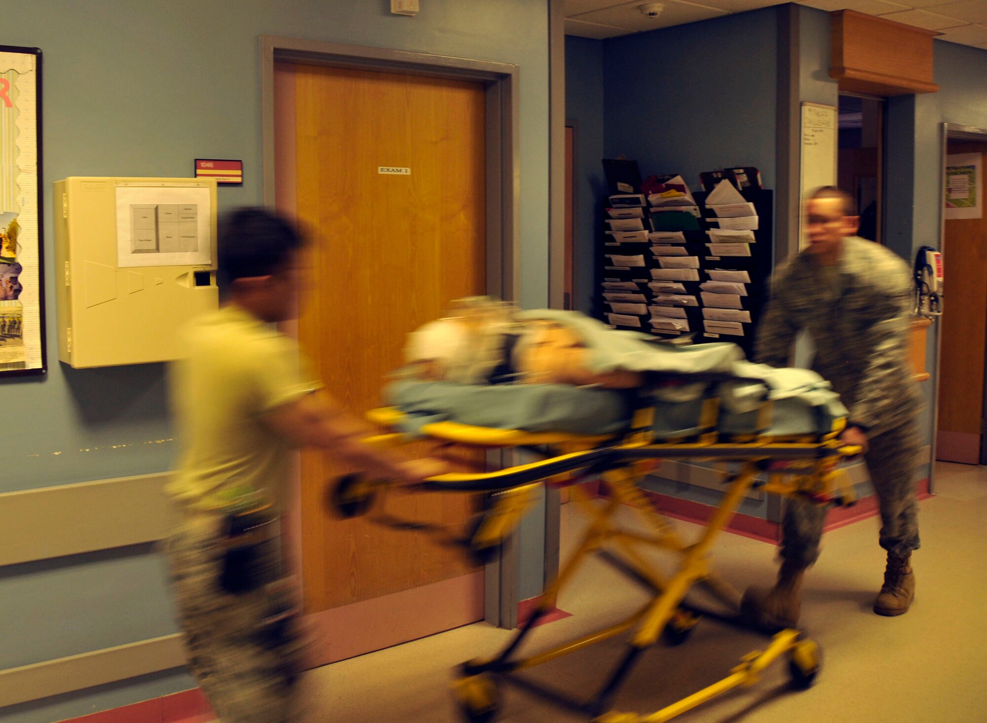 Staff Sgt. Vince Remo and Airman 1st Class Javier Urteaga, 48th Medical Operations Squadron emergency room technicians, transport Simon, a simulated patient down the hall of the emergency room at RAF Lakenheath, England.  The RAF Lakenheath ER also supports RAFs Mildenhall and Feltwell. (U.S. Air Force photo/Airman 1st Class Eboni Knox)