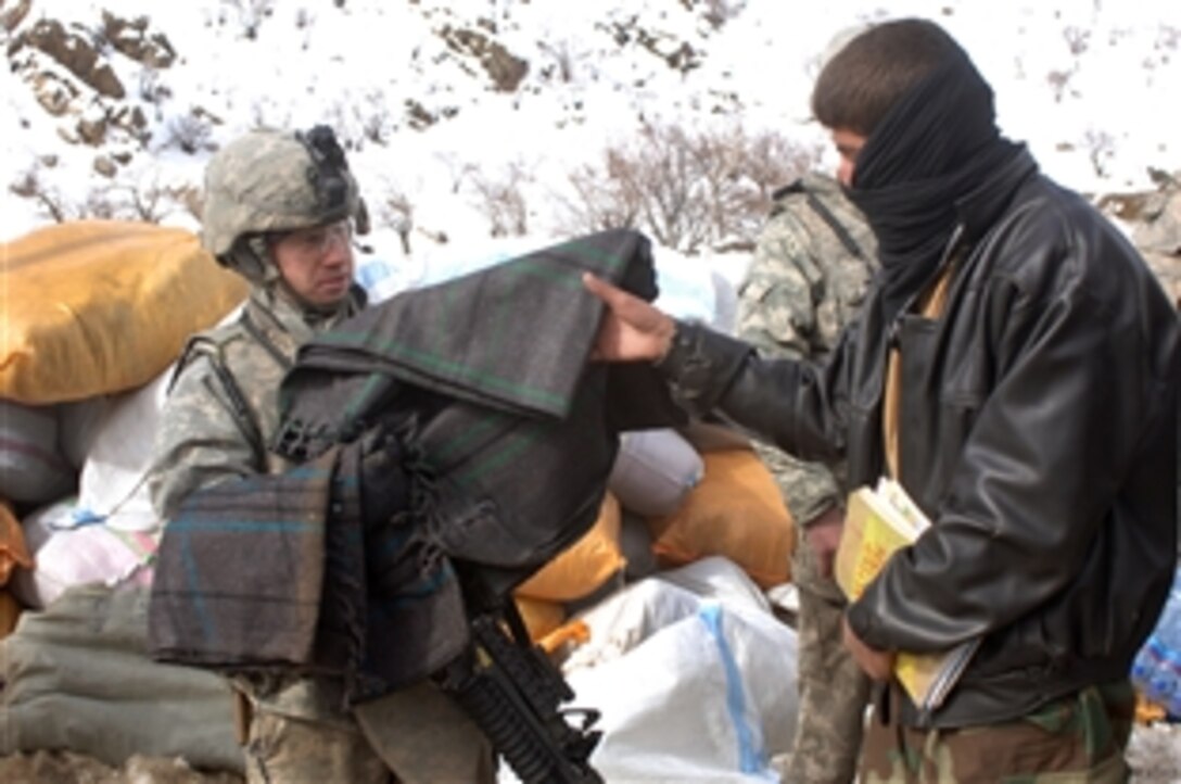 U.S. Army Sgt. John Newcomb passes out blankets to Afghans after a severe avalanche in the Salang district of Afghanistan, Feb. 10, 2010. Newcomb is a member of the 410th Military Police Company from Fort Hood, Texas. Other U.S. troops provided medical care to Afghans injured in the avalanche.