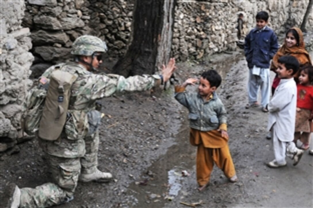 U.S. Army Spc. Jesus B. Fernandez greets children from Angla Kala village during a unit visit in Afghanistan's Kunar province, Feb. 6, 2010. International Security Assistance Force troops regularly meet with village elders to improve communications between residents and government officials. Fernandez is an assistant team leader assigned to the 2nd Battalion, 12th Infantry Regiment, 4th Brigade Combat Team.