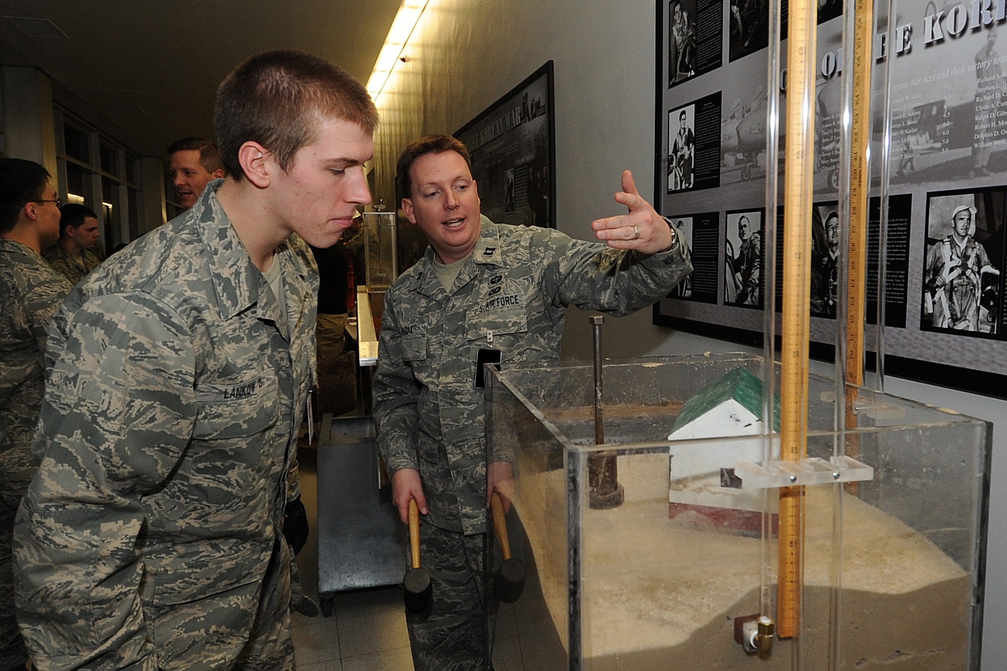 Capt. Jordan Hudak explains a display demonstrating the effects of earthquakes on buildings constructed atop soft ground to Cadet 4th Class Andrew Lankow during Majors' Night at the Air Force Academy Feb. 11, 2010. Captain Hudak is an instructor with the Department of Civil and Environmental Engineering. Cadet Lankow is assigned to Cadet Squadron 35. (U.S. Air Force photo/Rachel Boettcher)