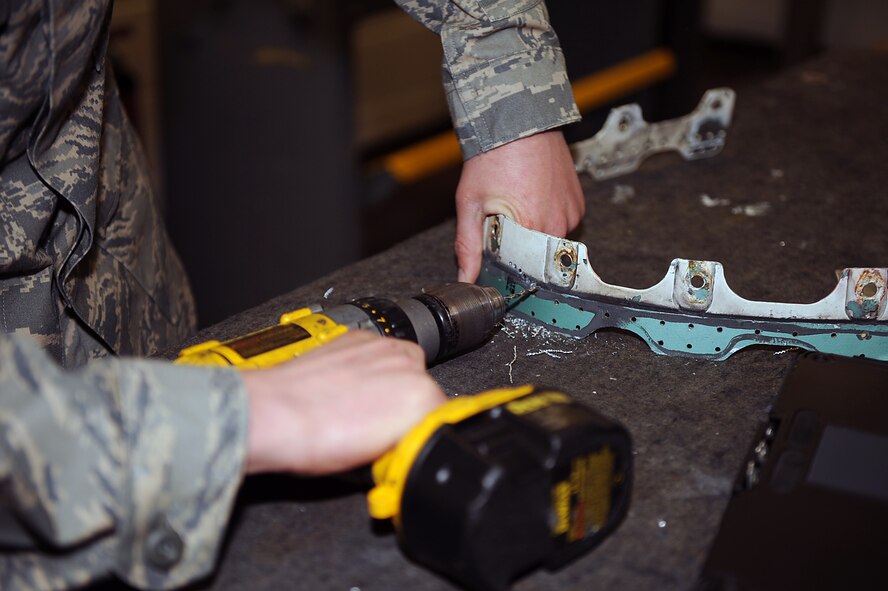 Senior Airman John McKenzie, 4th Equipment Maintenance Squadron aircraft maintenance journeyman, drills holes into an aircraft part to remove damage on Seymour Johnson Air Force Base, N.C., Feb. 12, 2010.  He will use the holes to secure a new piece of sheet metal with fasteners to patch the damaged area. McKenzie hails from Roseville, Calif. (U.S. Air Force photo/Senior Airman Ciara Wymbs) 