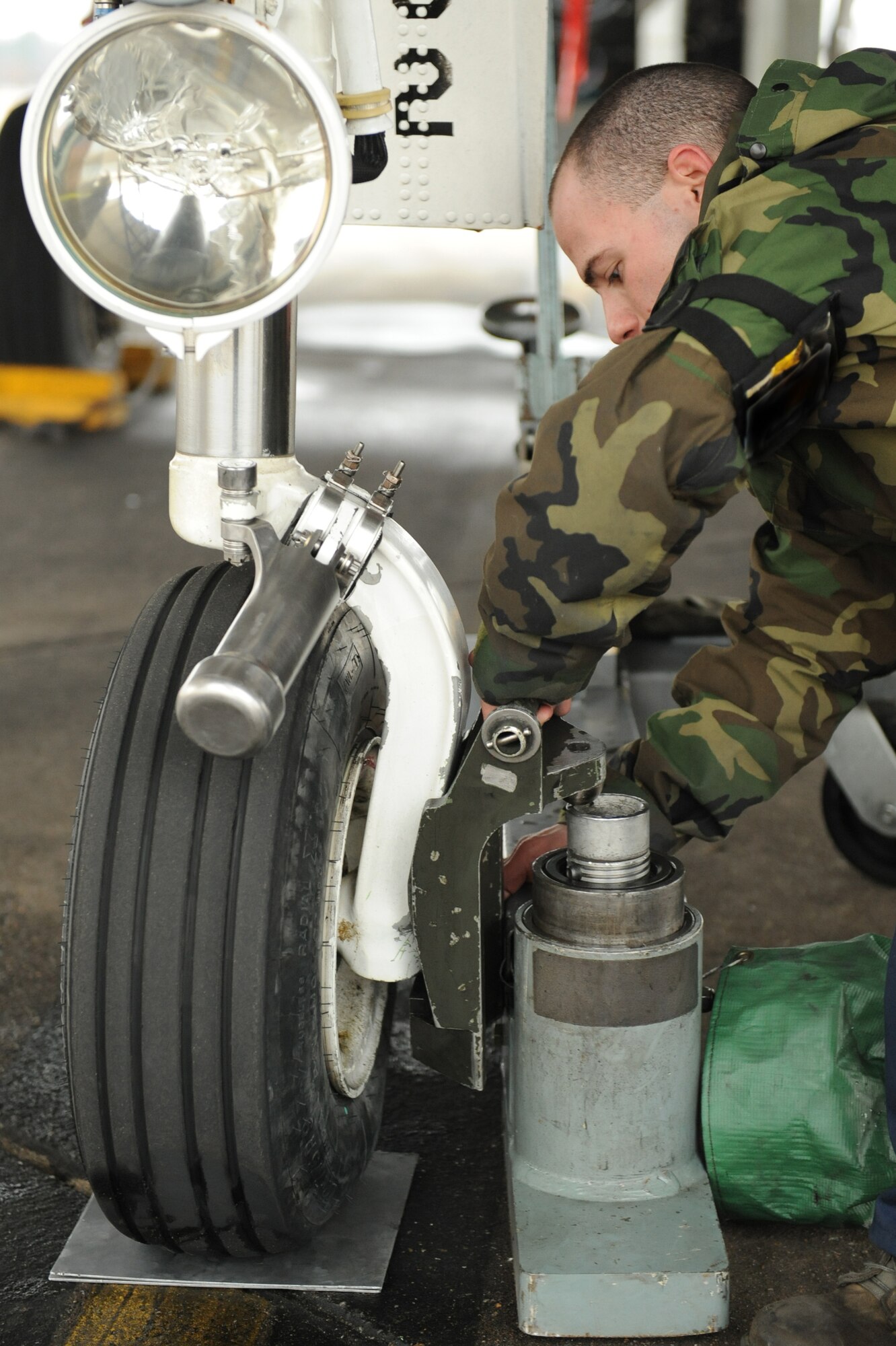 Airman 1st Class Steven Filton, 336th Aircraft Maintenance Unit crew chief, jacks-up the front tire of an F-15E Strike Eagle on Seymour Johnson Air Force Base, N.C., Feb. 9, 2010. Filton, from Savannah, Ga., is trouble shooting the nose forward door to correct its alignment. (U.S. Air Force photo illustration/Senior Airman Whitney Lambert)