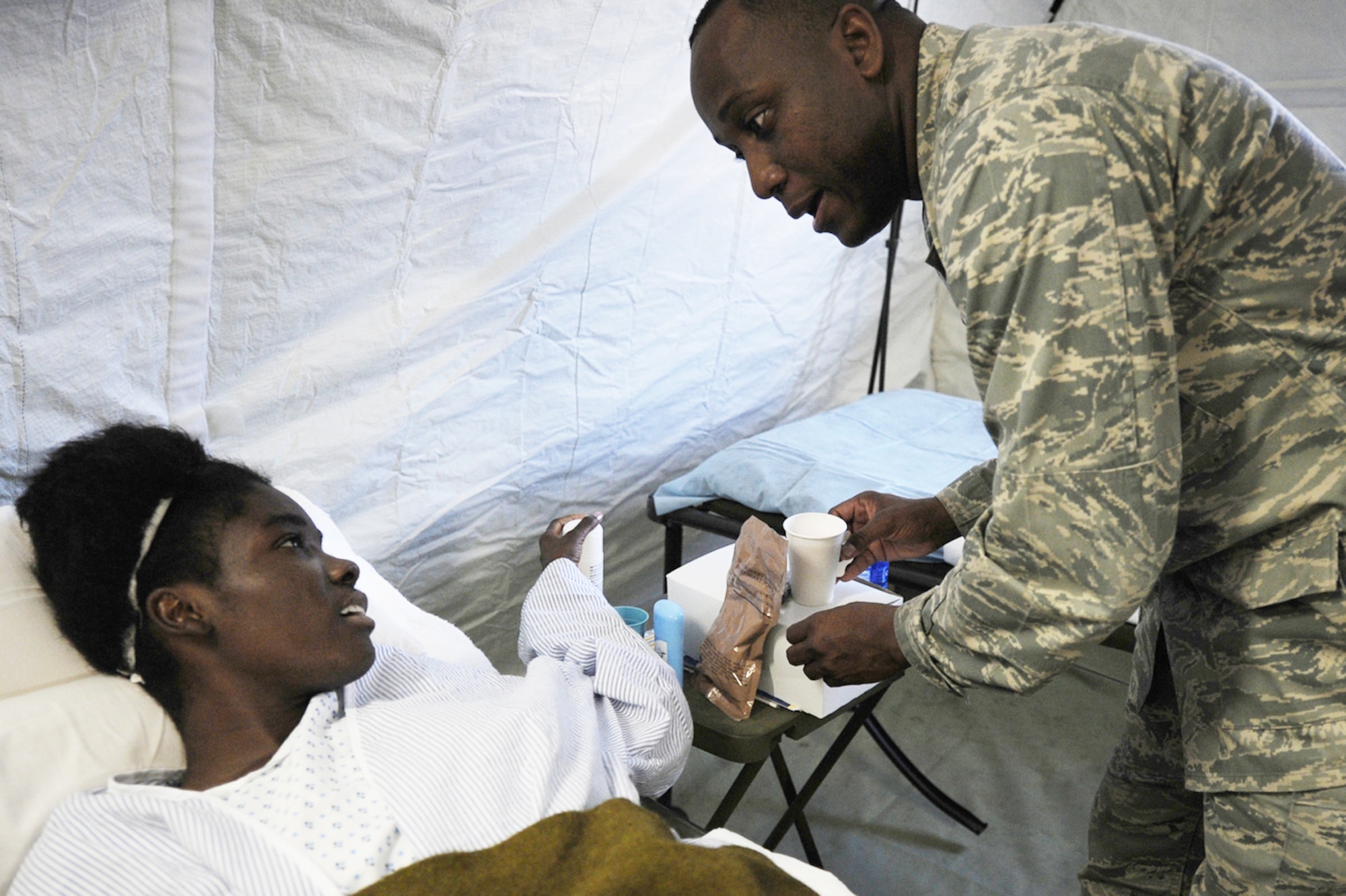 An Airman from Travis Air Force Base, Calif., treats an earthquake survivor at an expeditionary medical facility Feb. 3, 2010, located along the harbor of Port-au-Prince, Haiti. A 7.0-magnatude earthquake struck Haiti Jan. 12, leaving thousands of Haitians displaced and without access to food, water and vital medical care. (U.S. Navy photo/Petty Officer 2nd Class Todd Frantom)