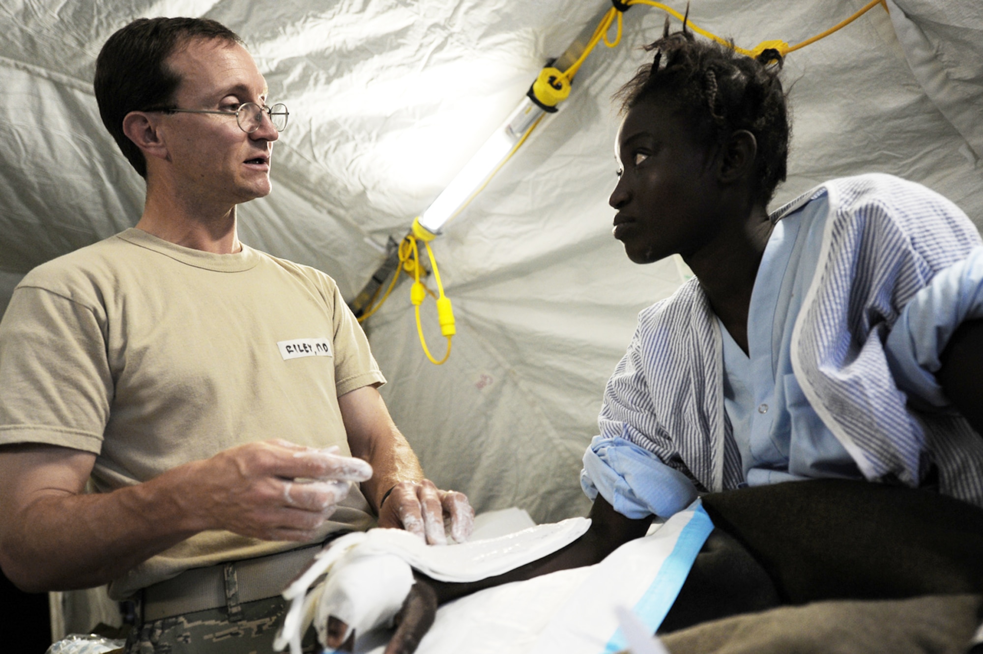 An Airman from Travis Air Force Base, Calif., treats an earthquake survivor at an expeditionary medical facility Feb. 3, 2010, located along the harbor of Port-au-Prince, Haiti. A 7.0-magnatude earthquake struck Haiti Jan. 12, leaving thousands of Haitians displaced and without access to food, water and vital medical care. (U.S. Navy photo/Petty Officer 2nd Class Todd Frantom)
