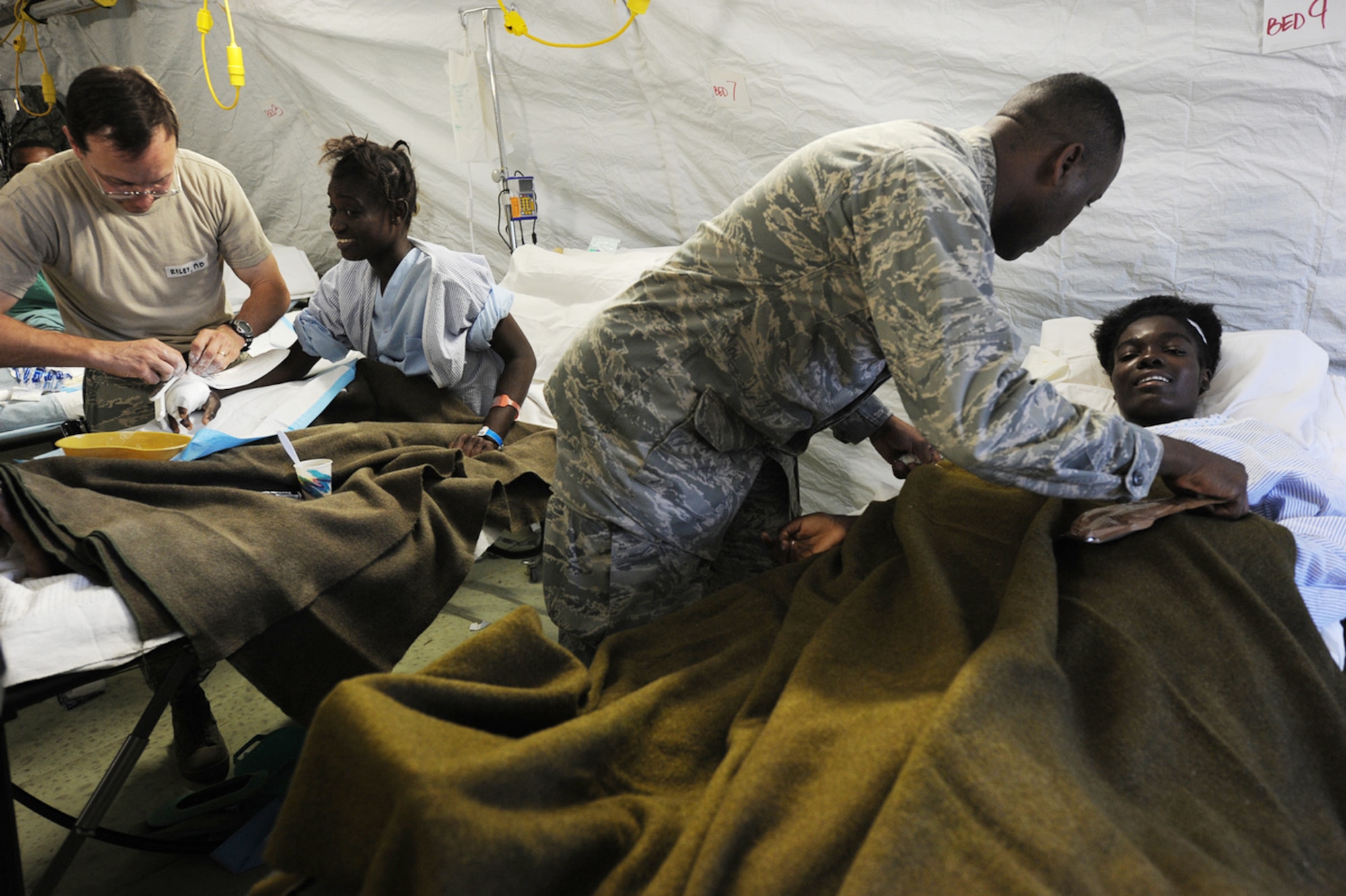 Airmen from Travis Air Force Base, Calif., and Navy corpsman treat earthquake survivors at an expeditionary medical facility Feb. 3, 2010, located along the harbor of Port-au-Prince, Haiti. A 7.0-magnatude earthquake struck Haiti Jan. 12, leaving thousands of Haitians displaced and without access to food, water and vital medical care. (U.S. Navy photo/Petty Officer 2nd Class Todd Frantom)