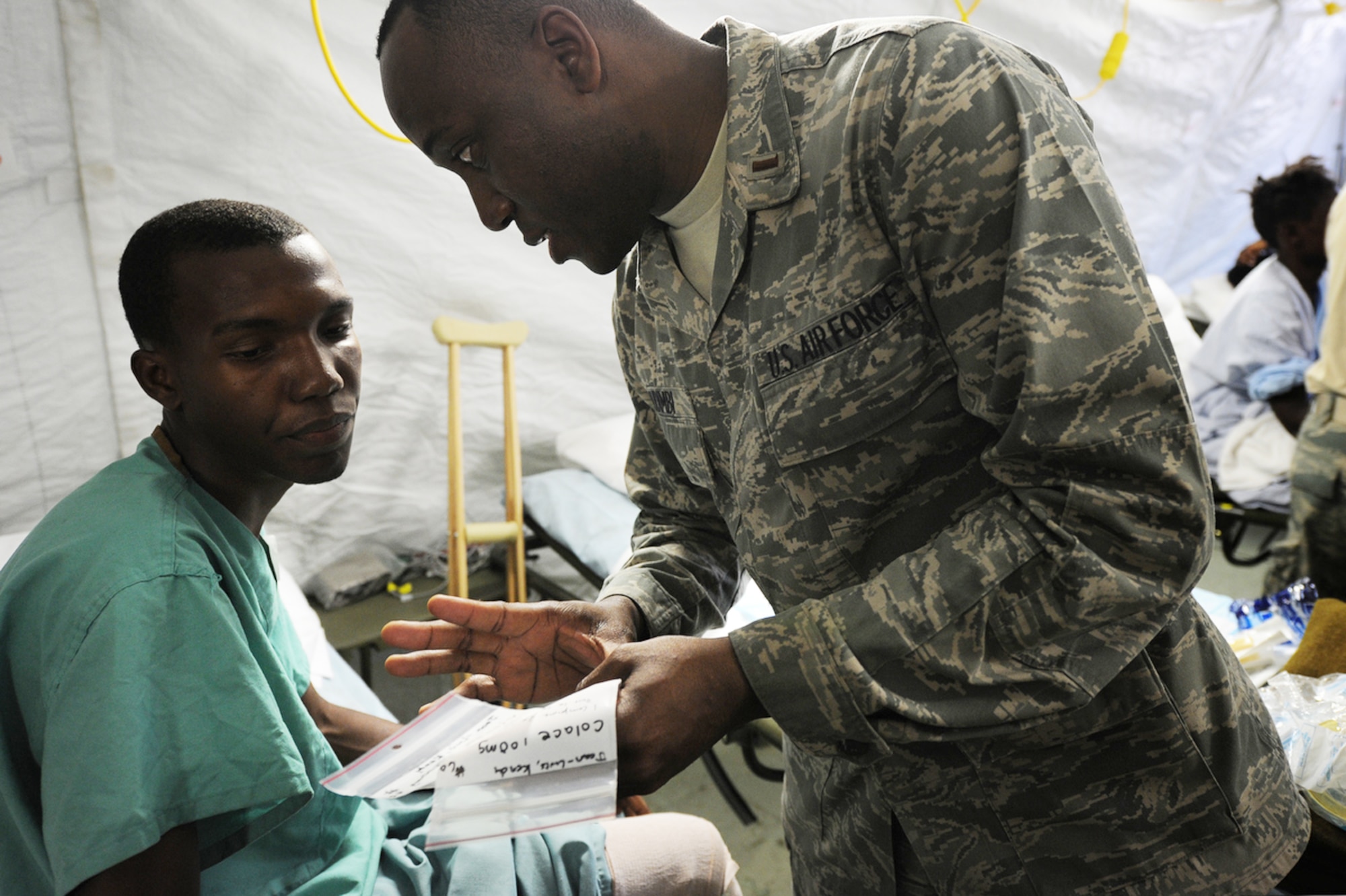 An Airman from Travis Air Force Base, Calif., treats an earthquake survivor at an expeditionary medical facility Feb. 3, 2010, located along the harbor of Port-au-Prince, Haiti. A 7.0-magnatude earthquake struck Haiti Jan. 12, leaving thousands of Haitians displaced and without access to food, water and vital medical care. (U.S. Navy photo/Petty Officer 2nd Class Todd Frantom)