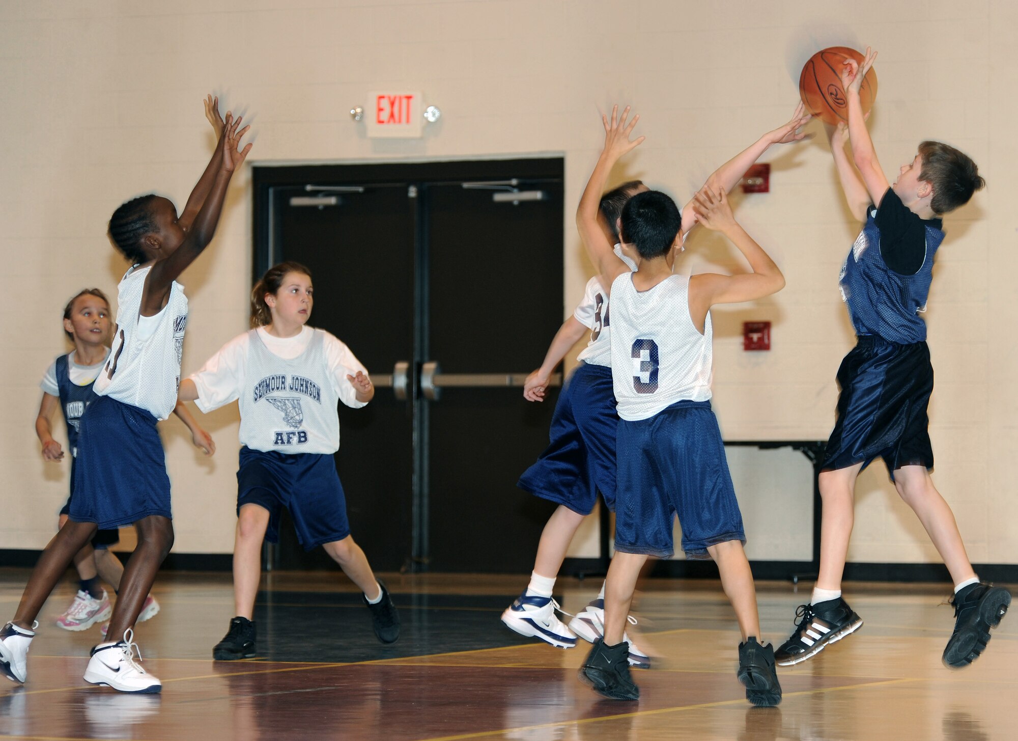 Sean Barry, Wolves guard, tips the ball as Tyler Chandler, Sharks center, shoots during a basketball game at the Seymour Johnson Air Force Base Youth Center Feb. 5, 2010.  The base youth programs do not keep an official score, but focus on fundamentals and having fun. Sean is the son of Staff Sgt. Thomas Barry, 4th Equipment Maintenance Squadron unit deployment manager, and Tyler is the son of Master Sgt. Robert Chandler, 333rd Aircraft Maintenance Unit production superintendent.  (U.S. Air Force photo/Tech. Sgt. Lesley Waters)