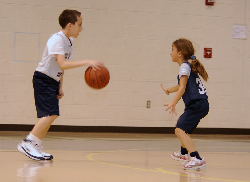 Sean Barry, Wolves guard, dribbles around Lauryn Freeman, Sharks guard, during a basketball game at the Seymour Johnson Air Force Base Youth Center Feb. 5, 2010.  Youth center basketball teams are broken up into four age groups for 5-to 12-year-old children.  Sean is the son of Staff Sgt. Thomas Barry, 4th Equipment Maintenance Squadron unit deployment manager, and Lauryn is the daughter of Tech. Sgt. Jeremy Freeman, 4th Component Maintenance Squadron aerospace propulsion craftsman. (U.S. Air Force photo/Tech. Sgt. Lesley Waters)