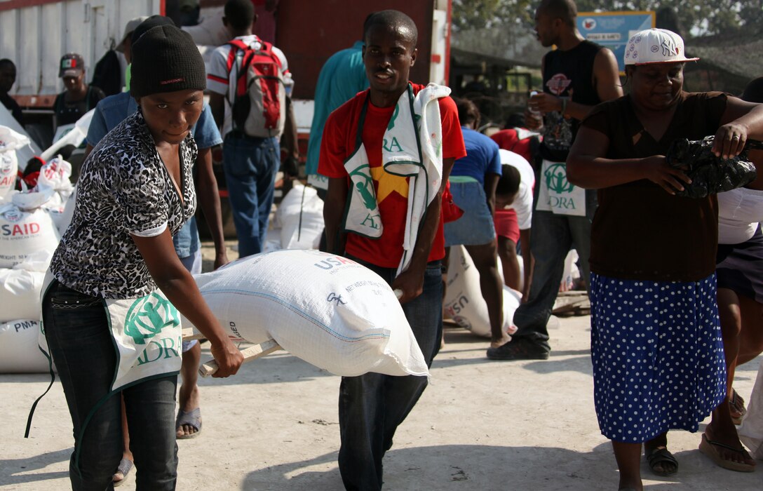 Local volunteers from Carrefour and the Port-au-Prince area working for Adventist Development Relief Agency, carry a bag of rice at a food distribution site in Carrefour, Haiti, Feb. 12, 2010. Marines from Battalion Landing Team, 3rd Battalion, 2nd Marine Regiment, 22nd Marine Expeditionary Unit, and United Nations Security Forces are assisting ADRA and the World Food Program during their major two-week distribution over the first half of February 2010.