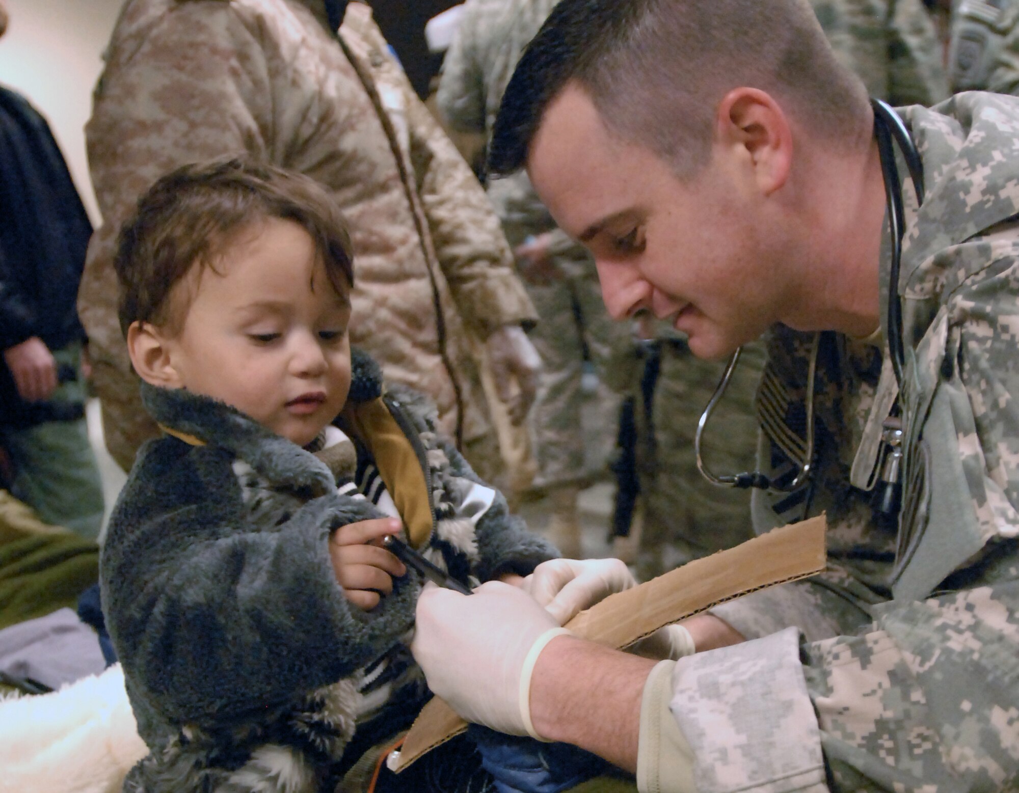 Lexington Park, Md., resident, Sgt. 1st Class Matthew Osborne, a medic with 3rd Infantry Division Combat Aviation Brigade, lets a child who was medically evacuated from the Salang district area avalanche in Parwan province, write with his pen at Bagram Airfield, Afghanistan, Feb. 9. Service members with Task Forces Cyclone, Falcon, Med and the 455th Air Expeditionary Wing, medically assisted hundreds of people rescued from the avalanche stricken area. (U.S. Army Photo/Spc. William Henry)