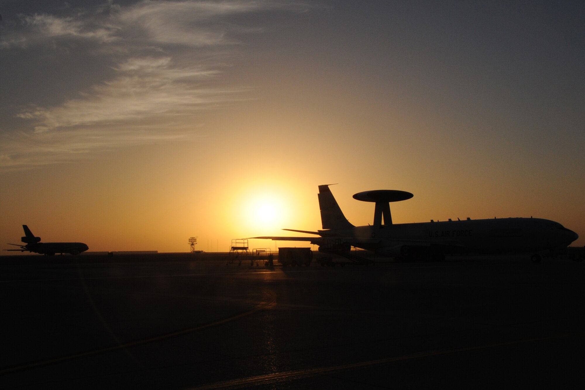 A E-3 Sentry Airborne Warning and Control System aircraft sits on the runway as a KC-10 Extender takes off at an undisclosed location in Southwest Asia on Feb.12, 2010.The E-3 Sentry is a modified Boeing 707/320 commercial airframe with a rotating radar dome that provides situational awareness of friendly, neutral and hostile activity, command and control of an area of responsibility, battle management of theater forces, all-altitude and all-weather surveillance of the battle space, and early warning of enemy actions during joint, allied, and coalition operations. The KC-10's primary mission is aerial refueling but can combine the tasks of a tanker and cargo aircraft by refueling fighters and simultaneously carry the fighter support personnel and equipment. (U.S. Air Force photo/Senior Airman Jenifer H. Calhoun/Released)
