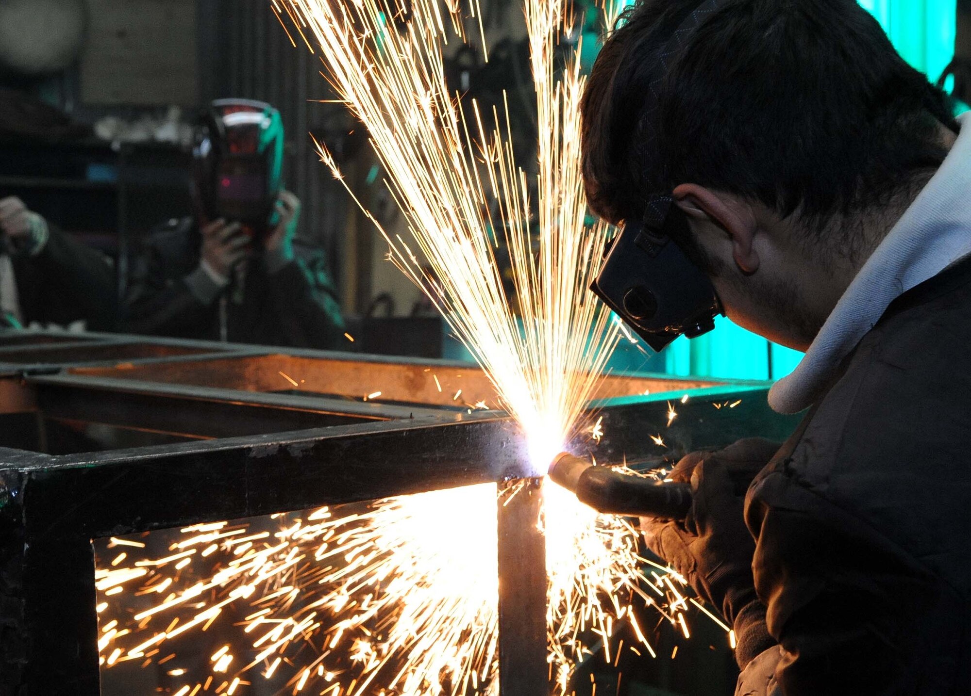 Azat Suerkulov, 376th Expeditionary Civil Engineer Squadron contractor, shows Jeni Jehr Vocational School students from Kyrgyzstan how to weld metal using proper personal protective equipment during their tour of the Transit Center at Manas Feb. 13. These students were touring the 376th ECES to see how Airmen conduct military operations here and learn different civil engineer techniques. (U.S. Air Force photo/Senior Airman Nichelle Anderson/released)